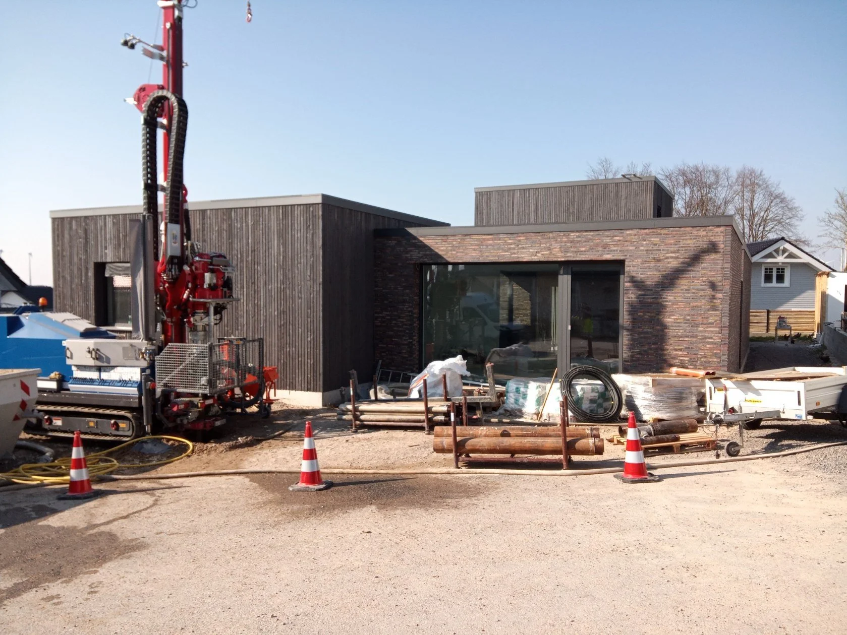 Modern house under construction with building equipment, construction cones, and building materials in the foreground.