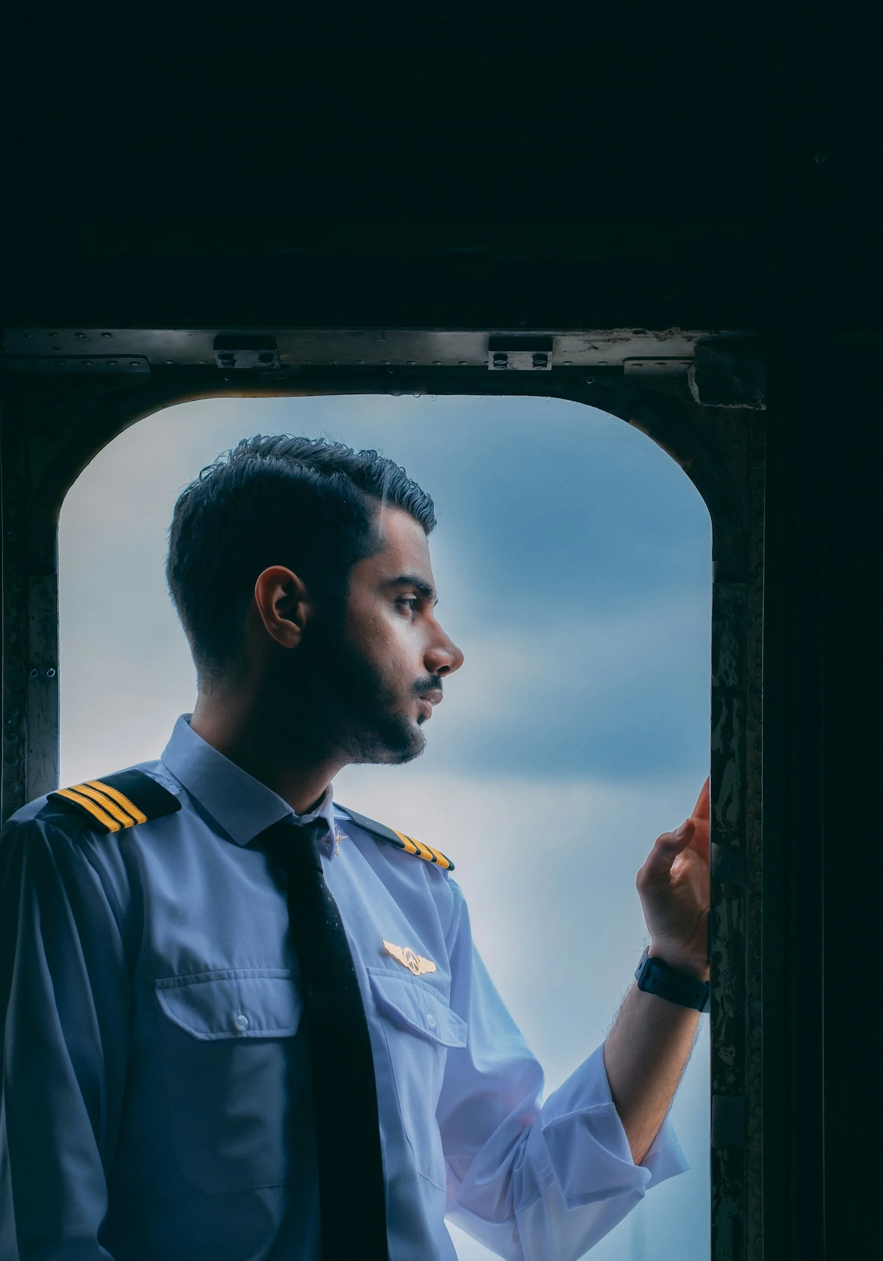 A contemplative pilot, an occupation with challenging bathroom access, rests in the window of an aircraft before flight.