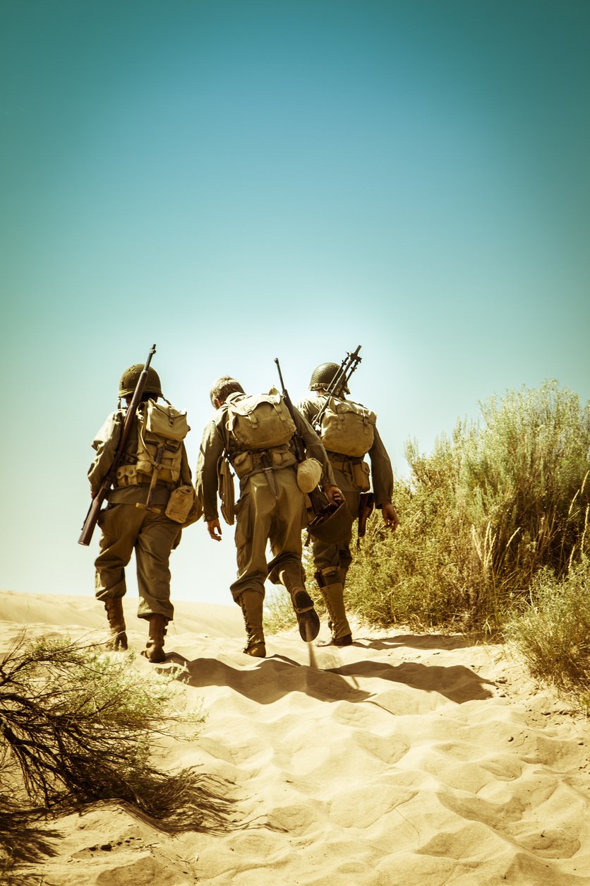 Three military service members walking with gear, highlighting occupational toxin exposures like burn pits and water contamination in an active duty health portfolio.