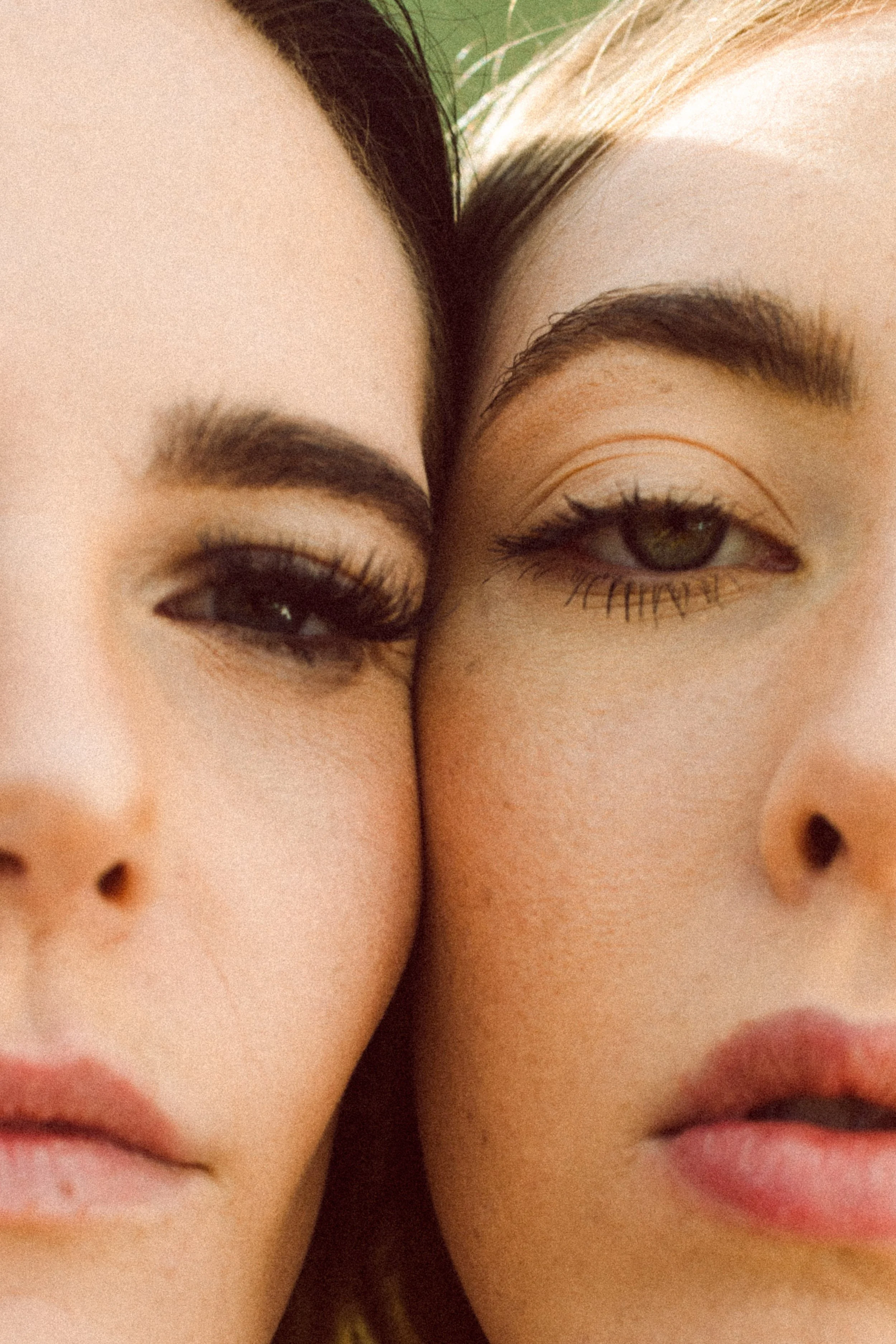 Close-up portrait of two fashion models with their faces touching, highlighting makeup, skin texture, and facial features.
