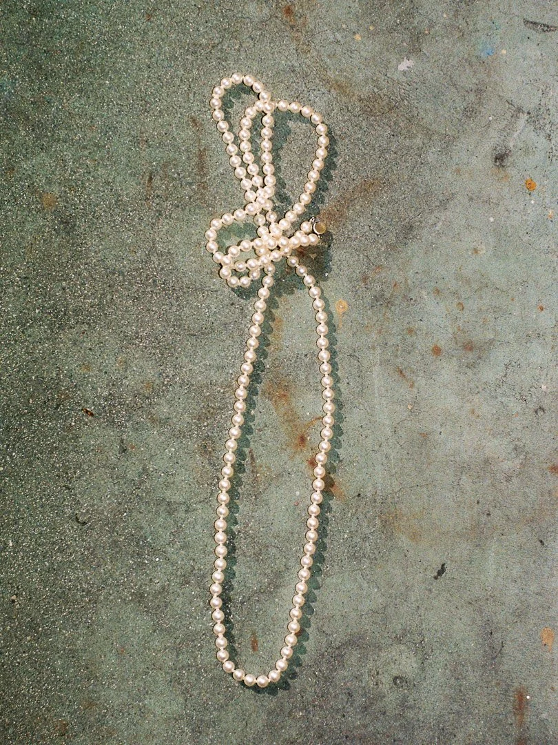 String of white pearl beads resting on a gray concrete surface.