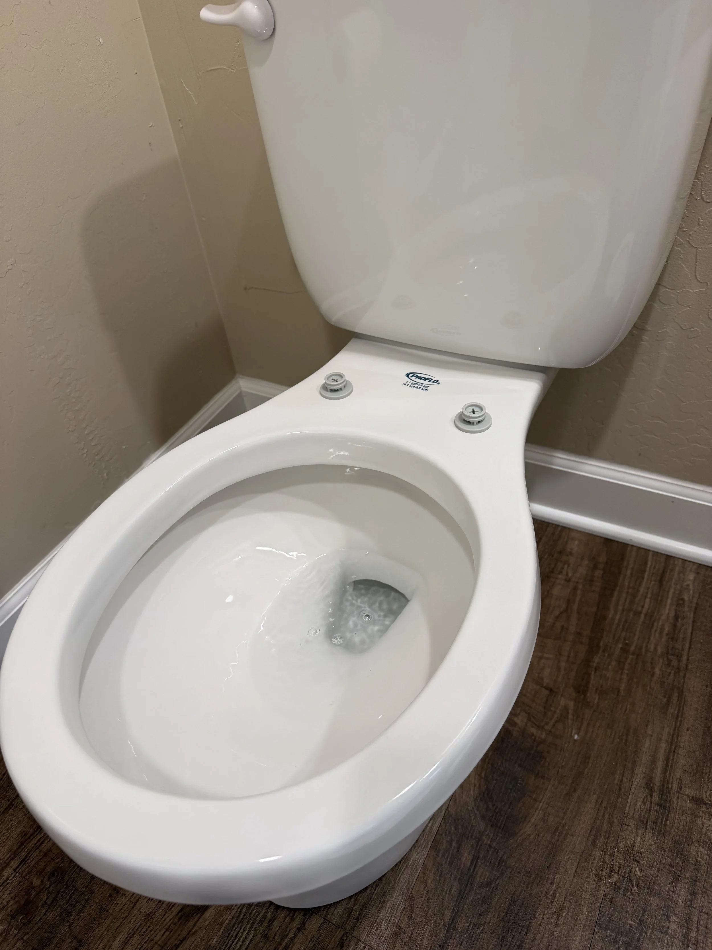 Toilet with the lid open and water filling the bowl.