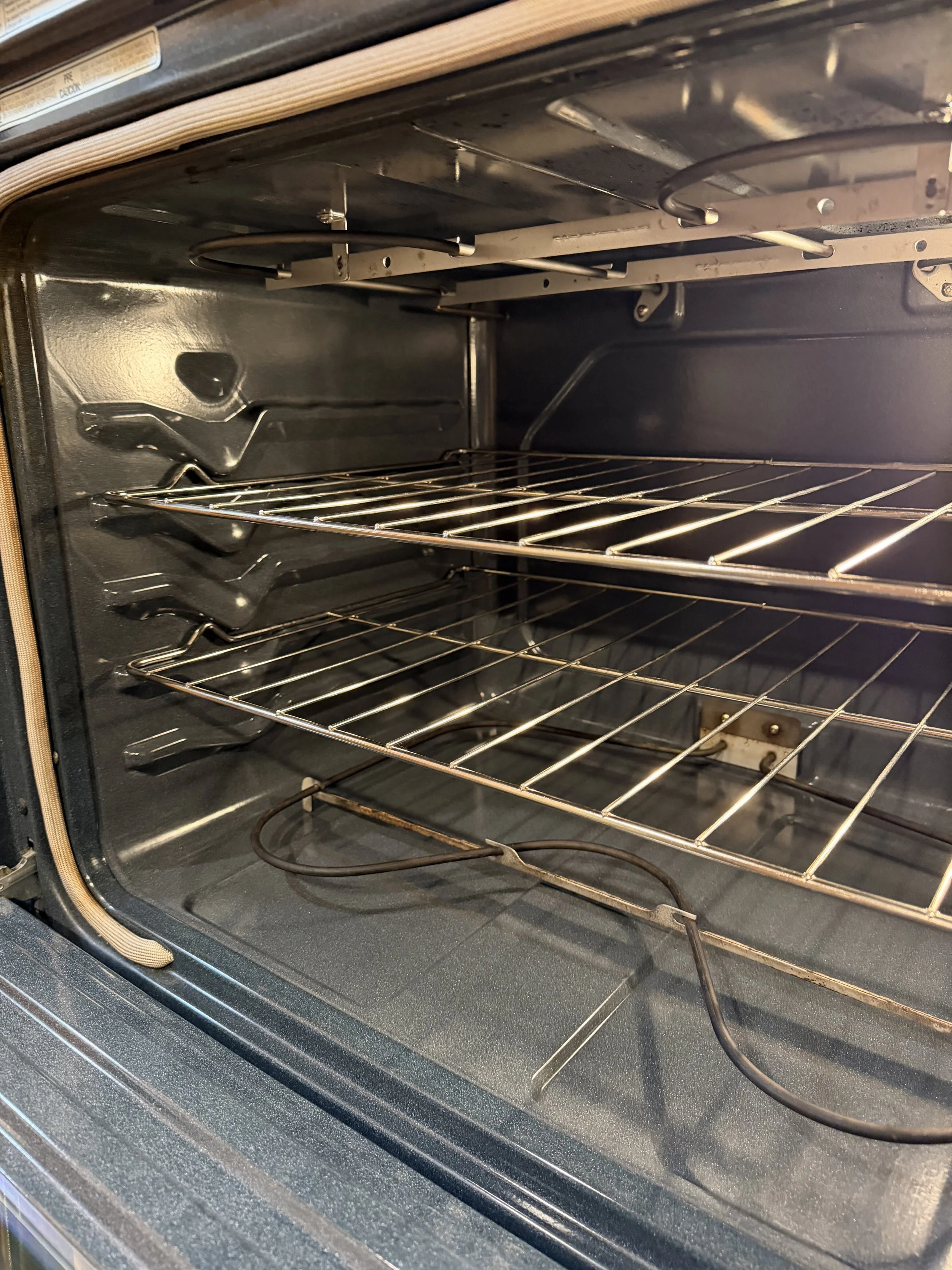 Empty electric oven with metal racks and heating elements.