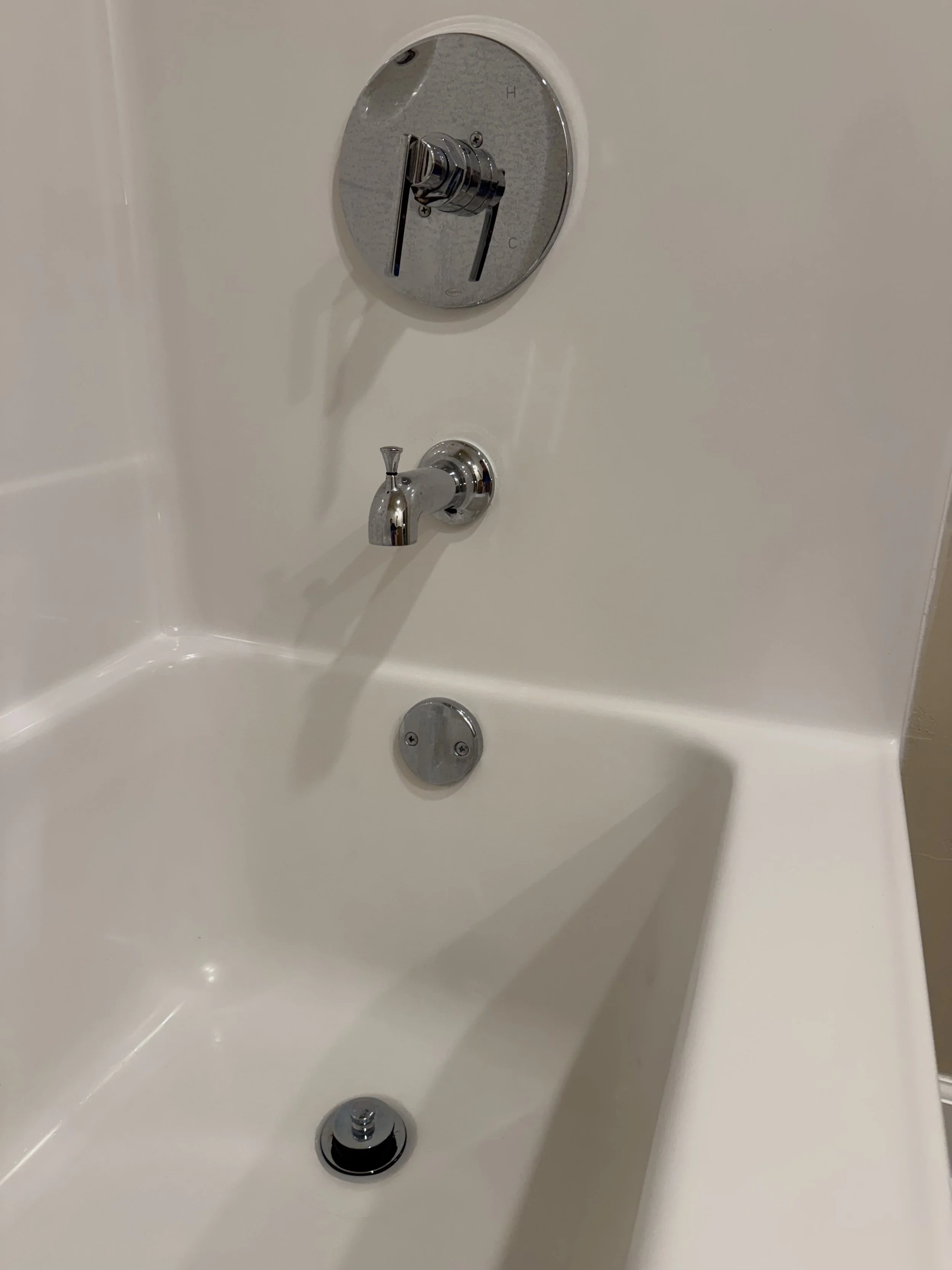 Close-up of bathtub faucet and temperature control knob, with drain at the bottom.