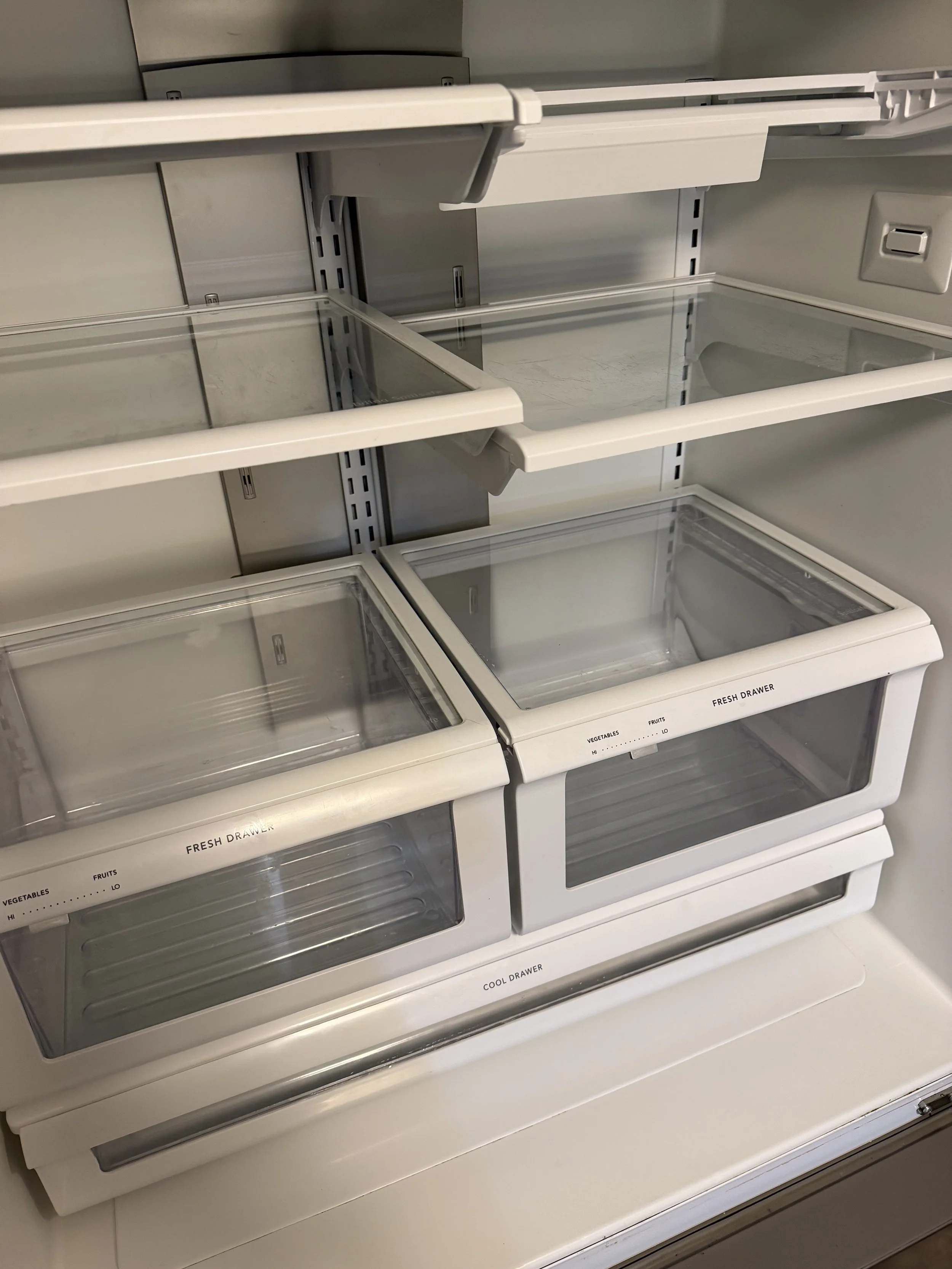Empty refrigerator with multiple glass shelves and labeled drawers, including a 'Fresh Drawer' and a 'Cool Drawer'.