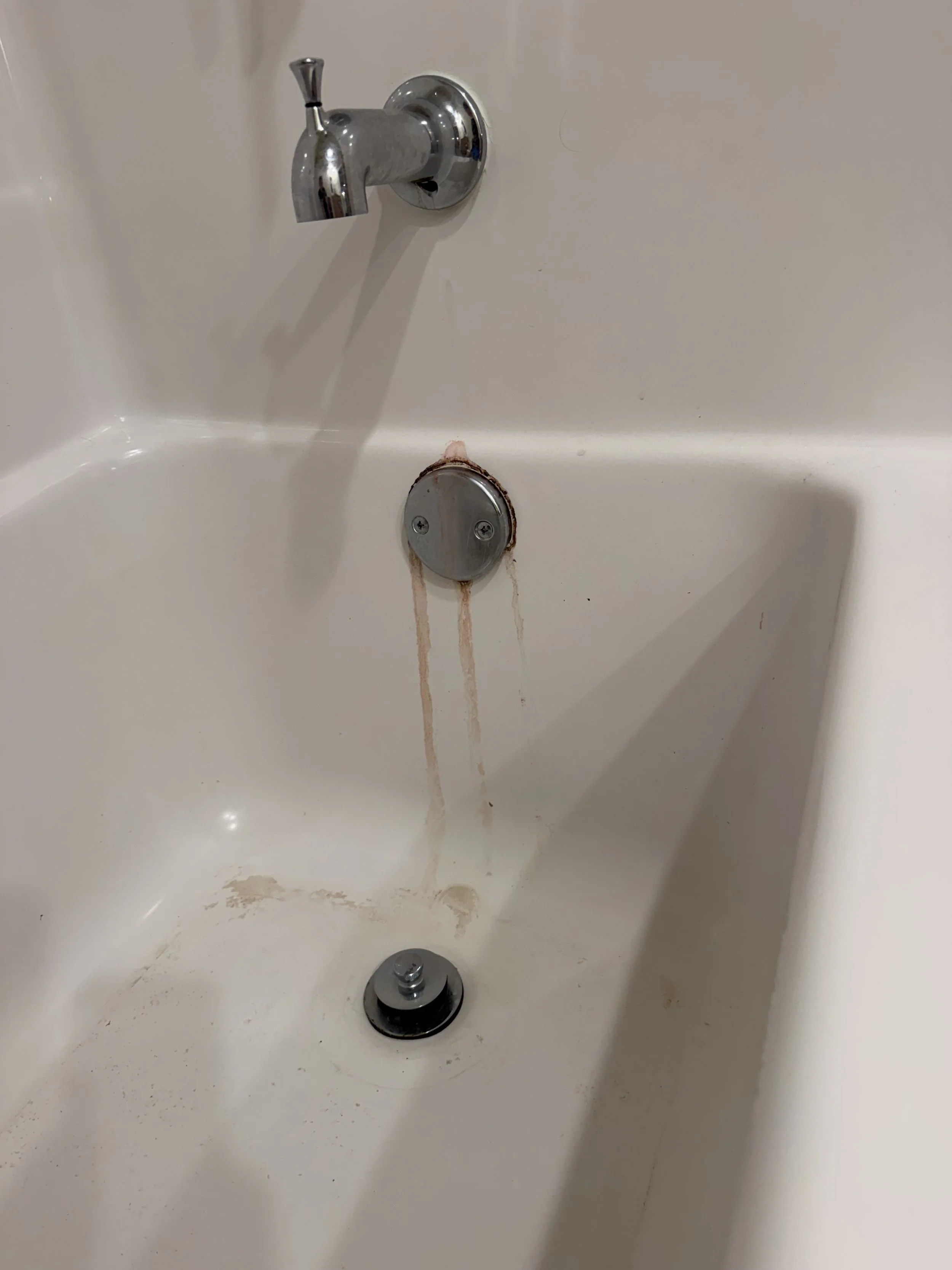 Dirty bathtub with a leaky faucet and water stains.