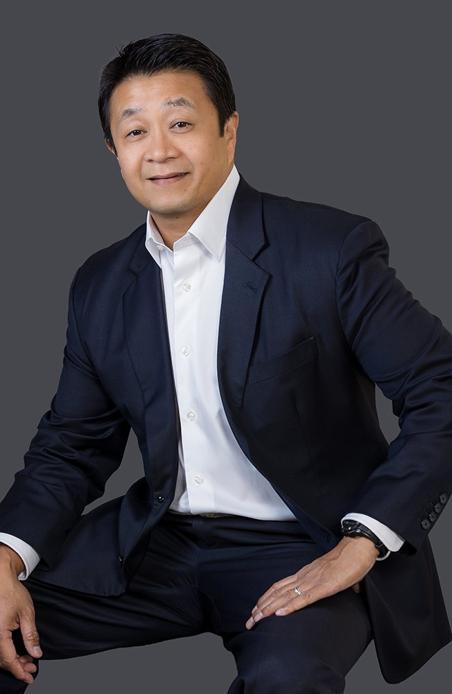 Executive headshot of a man in a dark suit, seated