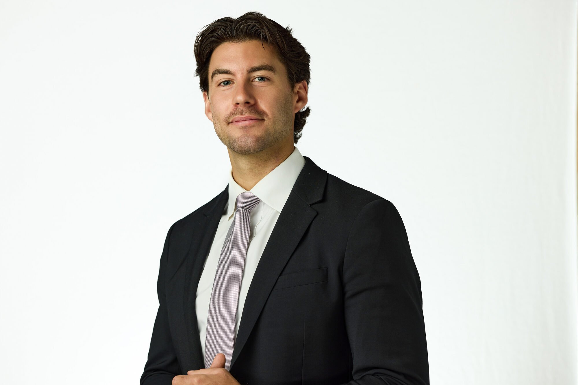 Executive headshot in a black suit, white background, New York on-location corporate session