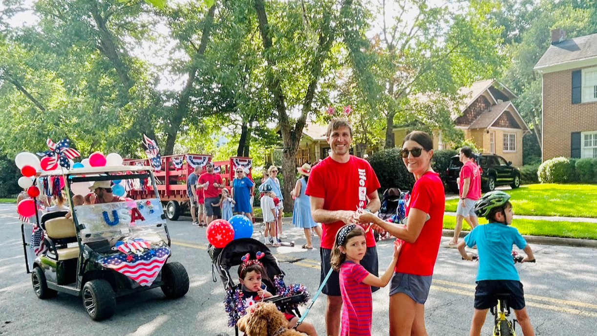 People celebrating the 4th of July in a parade with decorated vehicles and children, in Macon, Georgia's Historic Ingleside Neighborhood.