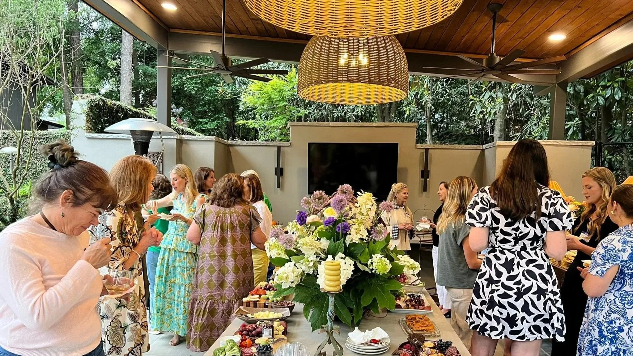 Annual HINA Ladies' Night, featuring at a beautiful buffet table with flowers, food, and drinks in a semi-outdoor space with trees and ceiling fans.