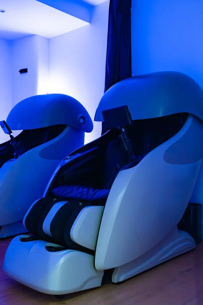 Close-up of two high-tech sports massage chairs with a touch screen in front of each one.