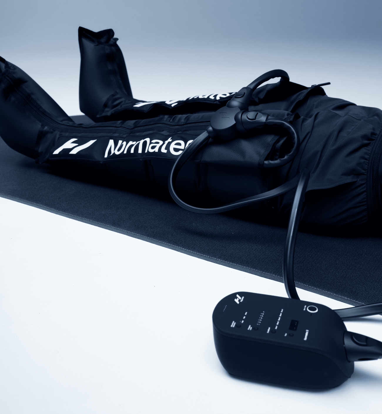 Close up of Normatec (Hyperice) compression boots, connected to its hyperice control centre, set on a yoga or stretching mat