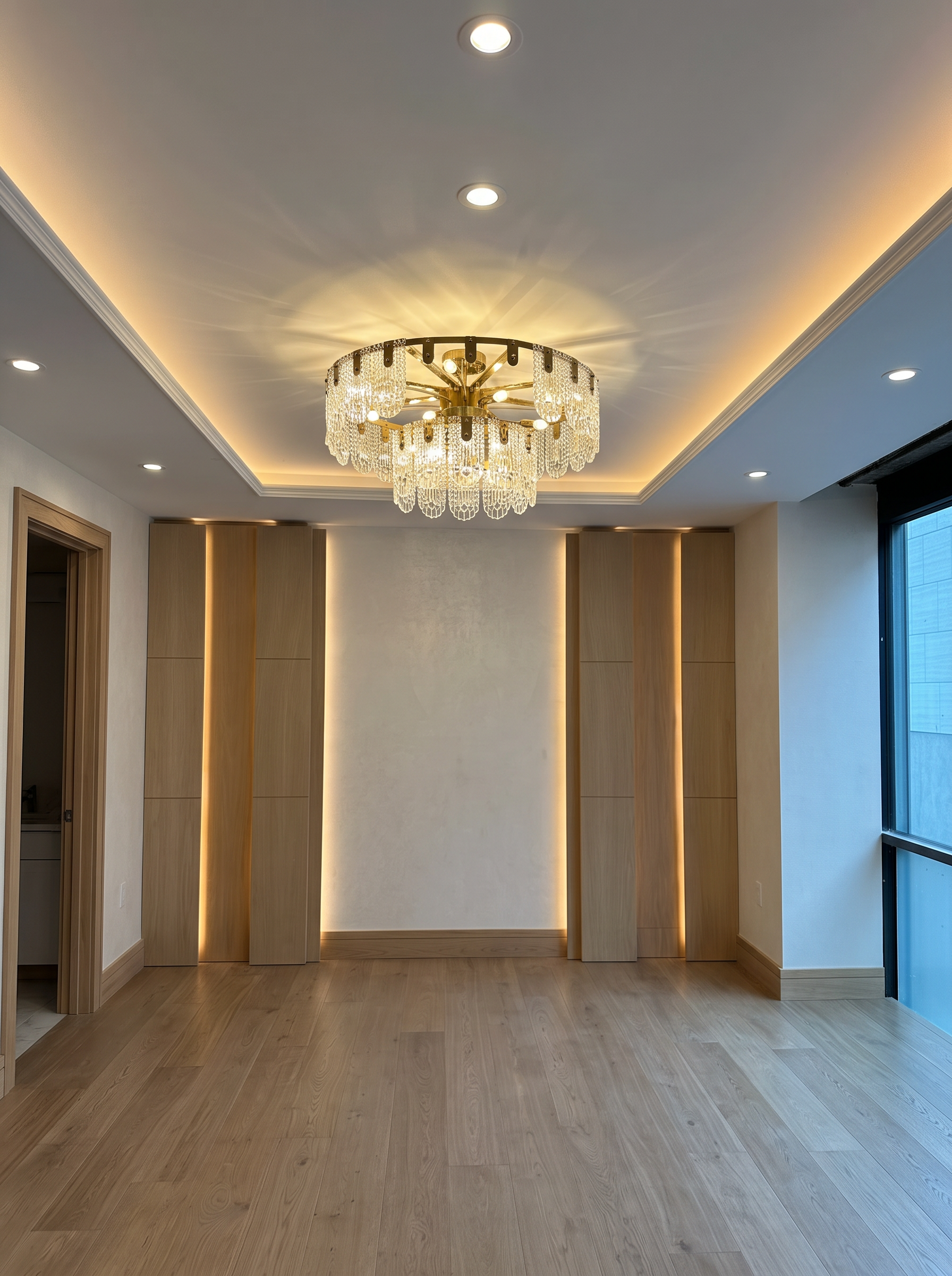 Interior room with a modern chandelier and recessed ceiling lights, wooden wall panels, and hardwood flooring.