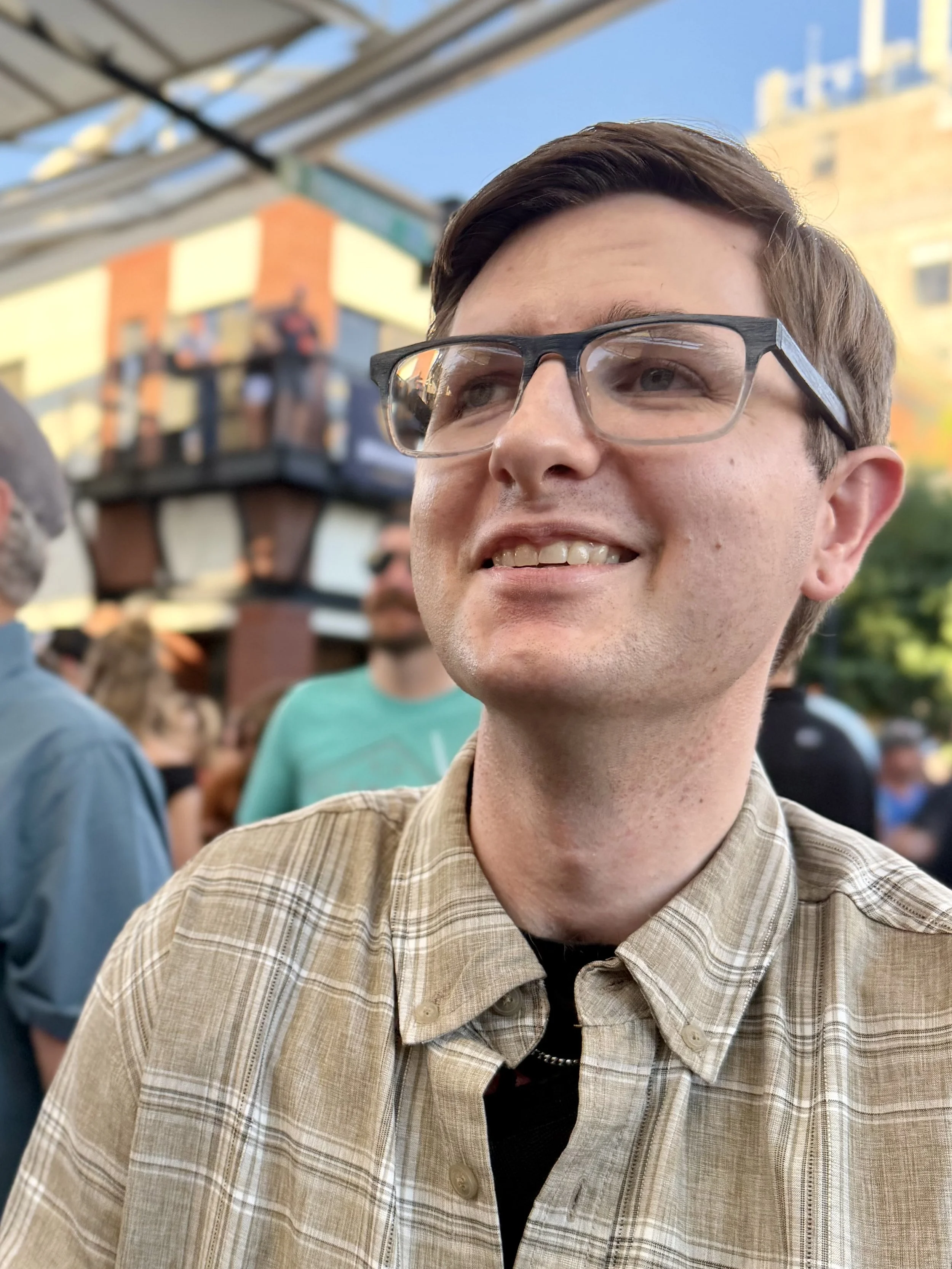 A man smiles and looks up while outdoors