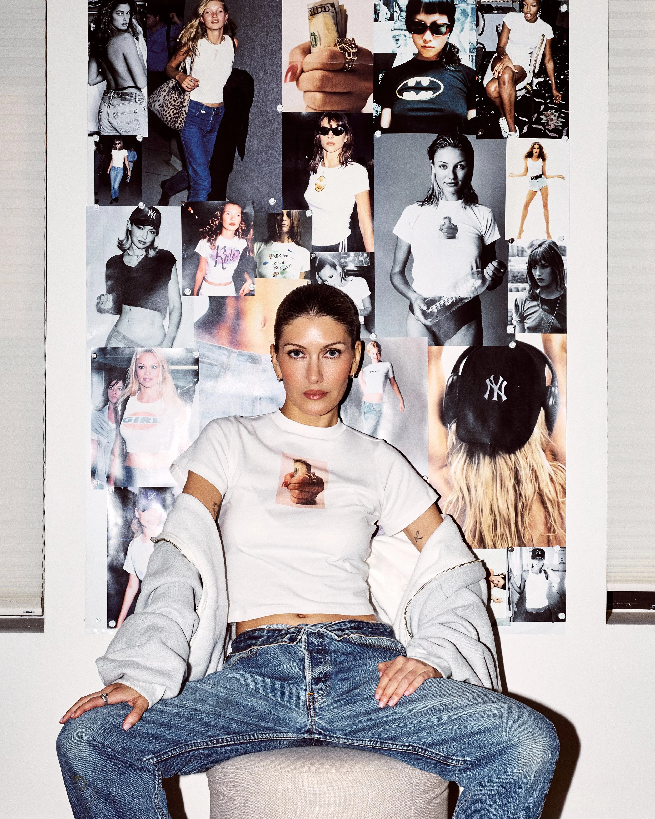 Woman seated in a white Ladi Da Printed Baby Tee and blue jeans in front of a fashion image collage.