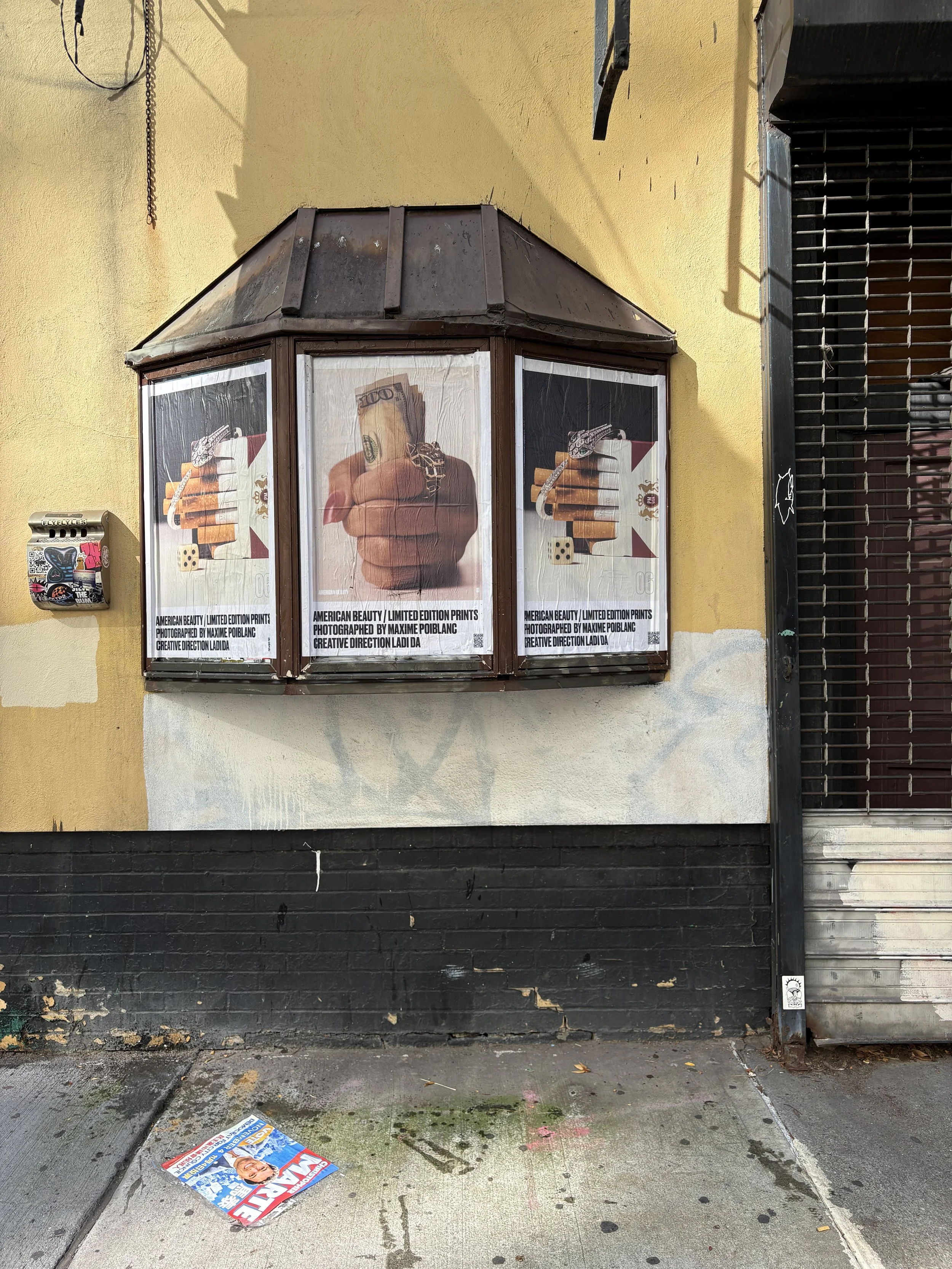 Street kiosk displaying repeated posters featuring the Ladi Da cash-in-hand artwork