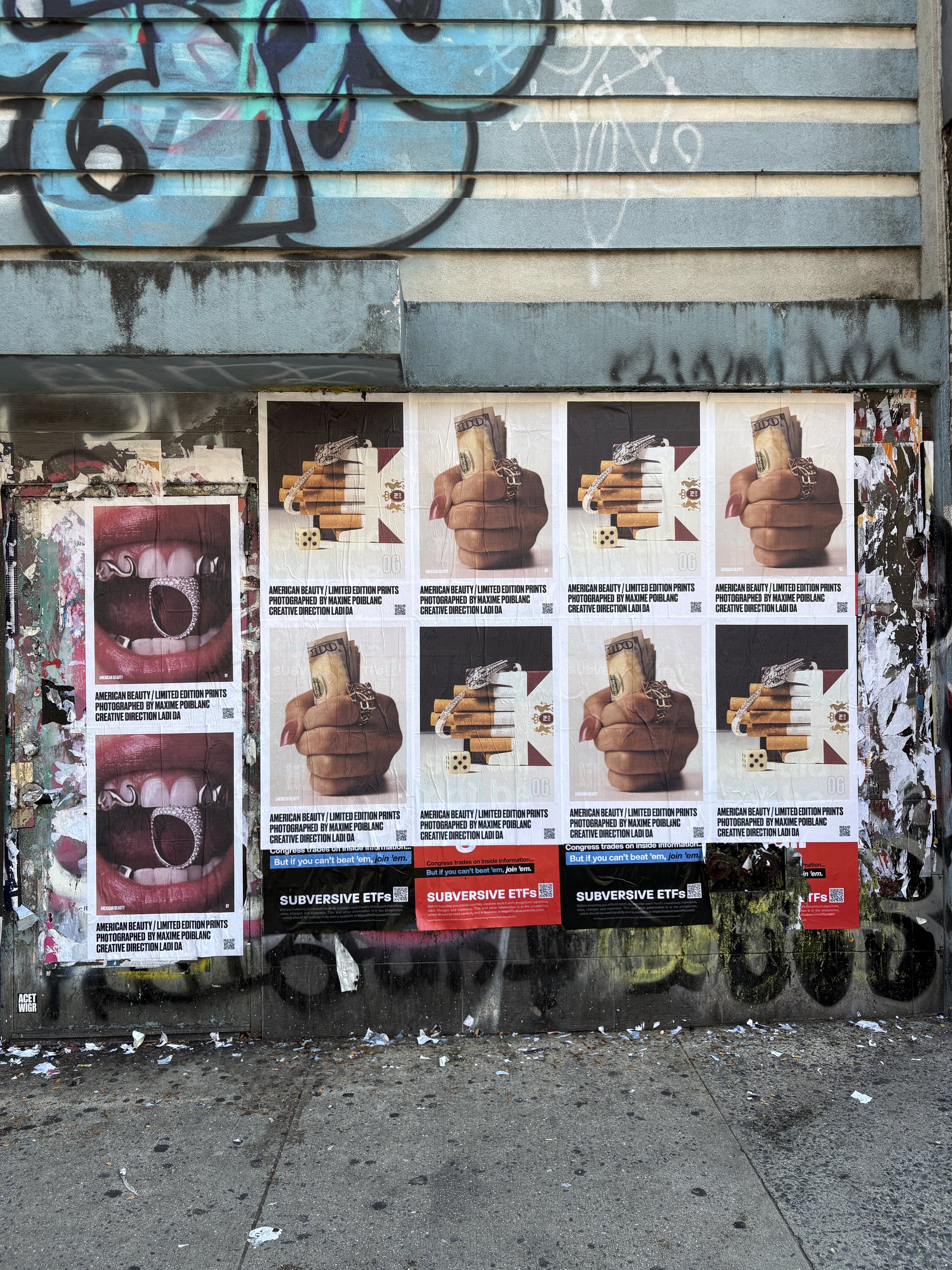 Street wall covered with repeated posters featuring the Ladi Da cash-in-hand artwork, layered over graffiti and other advertisements.