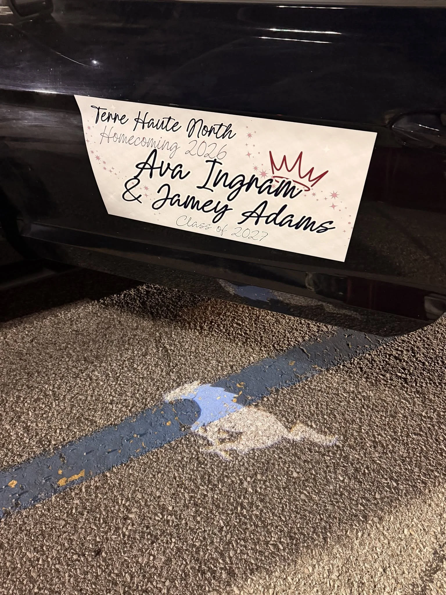 A poster on a car door announcing Terre Haute's High School Homecoming 2026 with the name Ava Ingram and Jamery Adams and a birthday crown drawn. The poster also mentions class of 2027, surrounded by stars and sparkles.