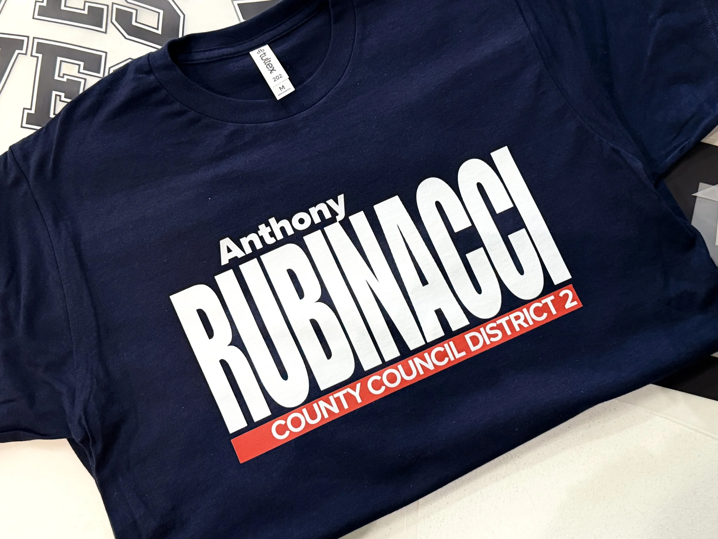 A navy blue T-shirt with white and red text supporting Anthony Buchanan, a candidate for County Council District 2.