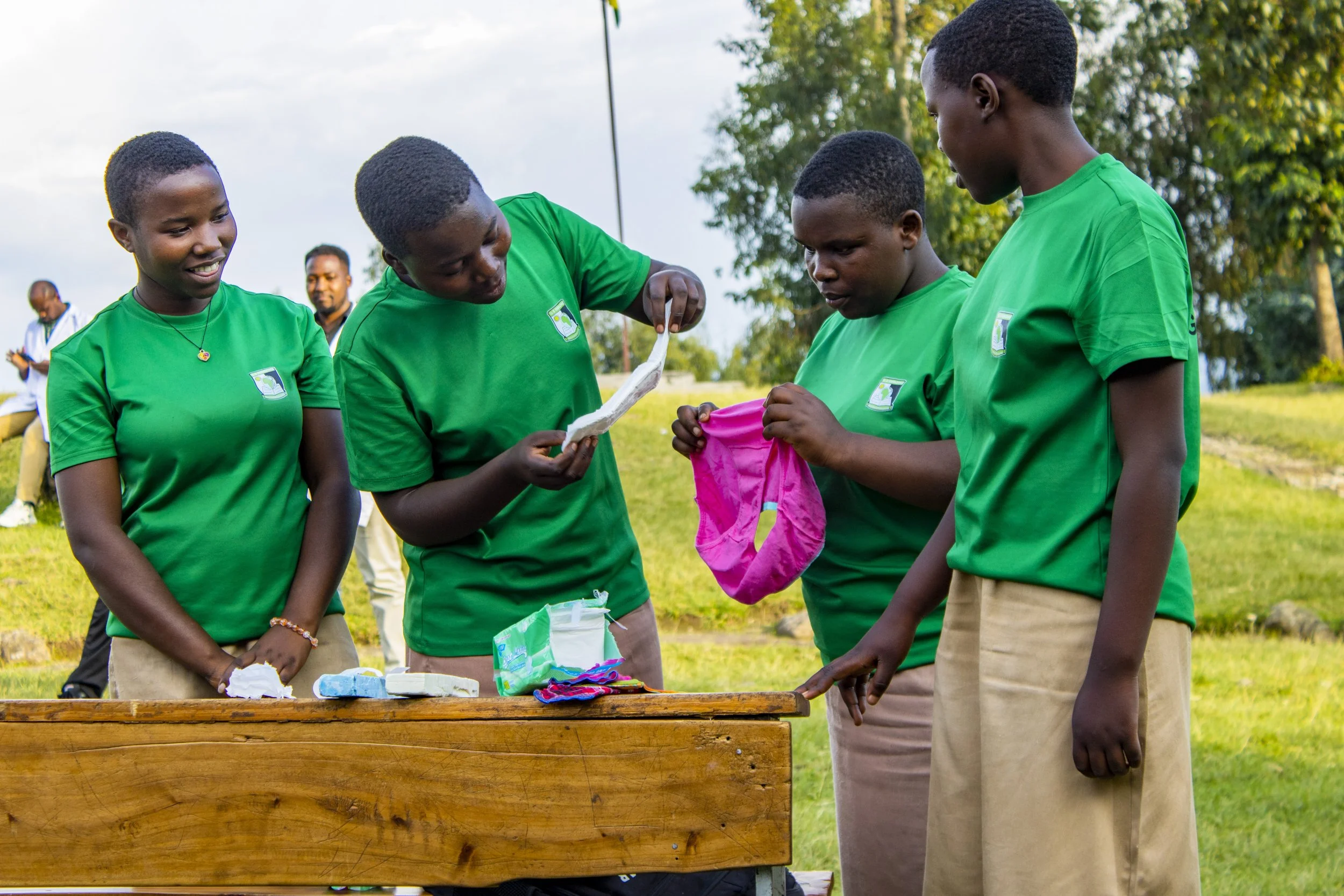 Students in green uniforms take part in an outdoor handwashing activity.