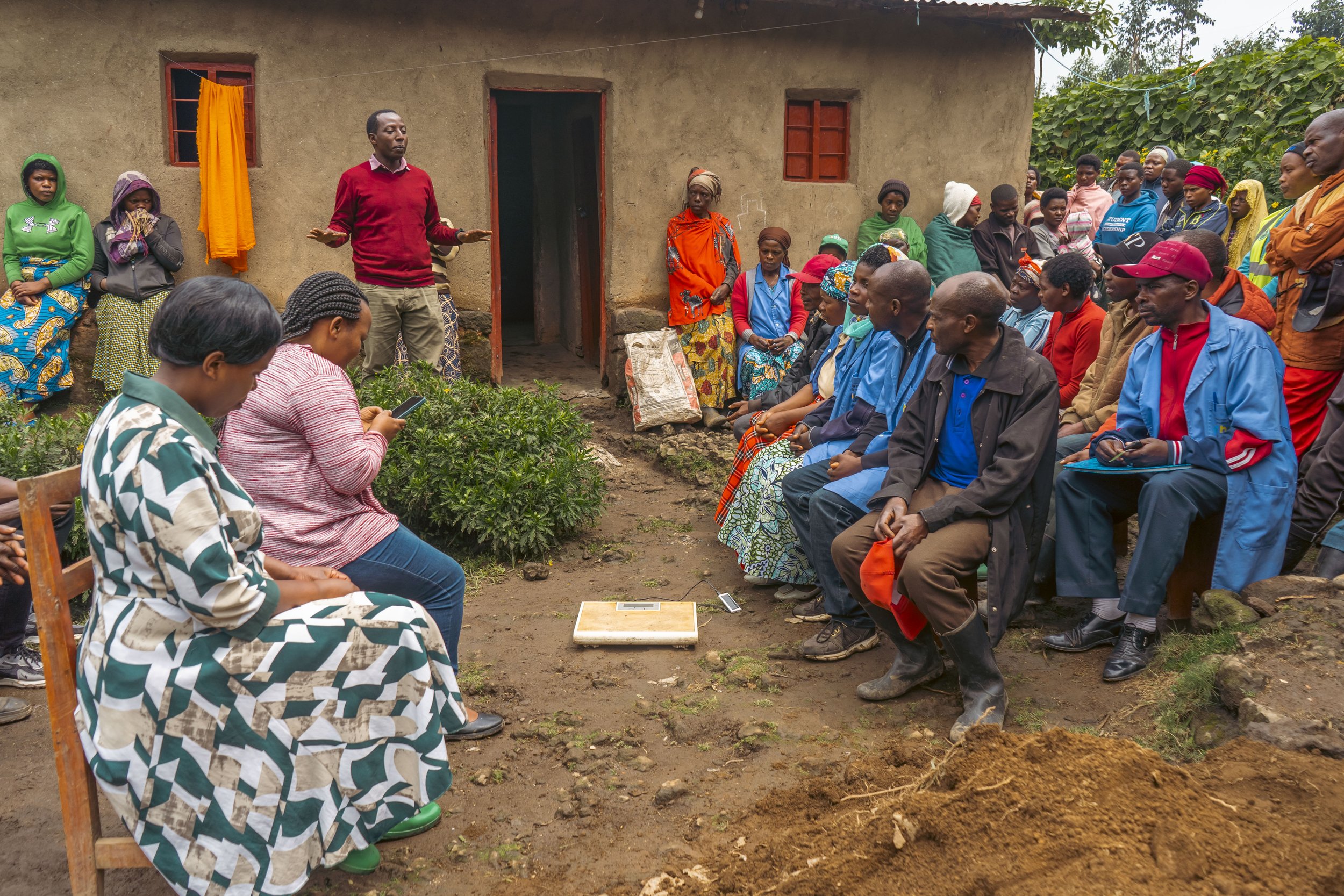 Adults and children gather outside a building for a community discussion.