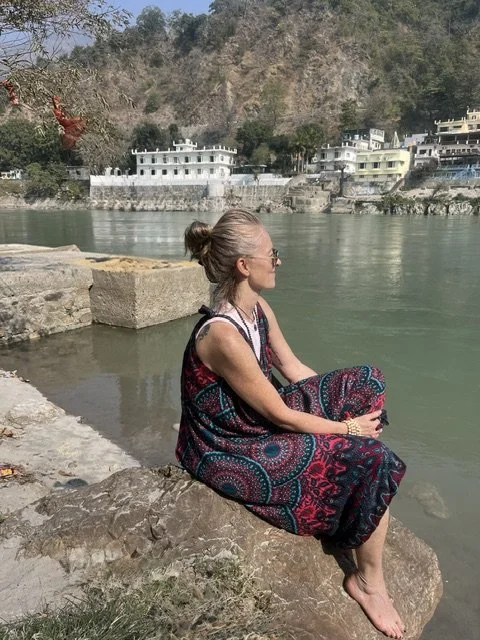 Tanya Johnson, founder of Rooted yogi.ca meditating in Rishikesh    by the Ganges in India, embracing stillness and inner peace