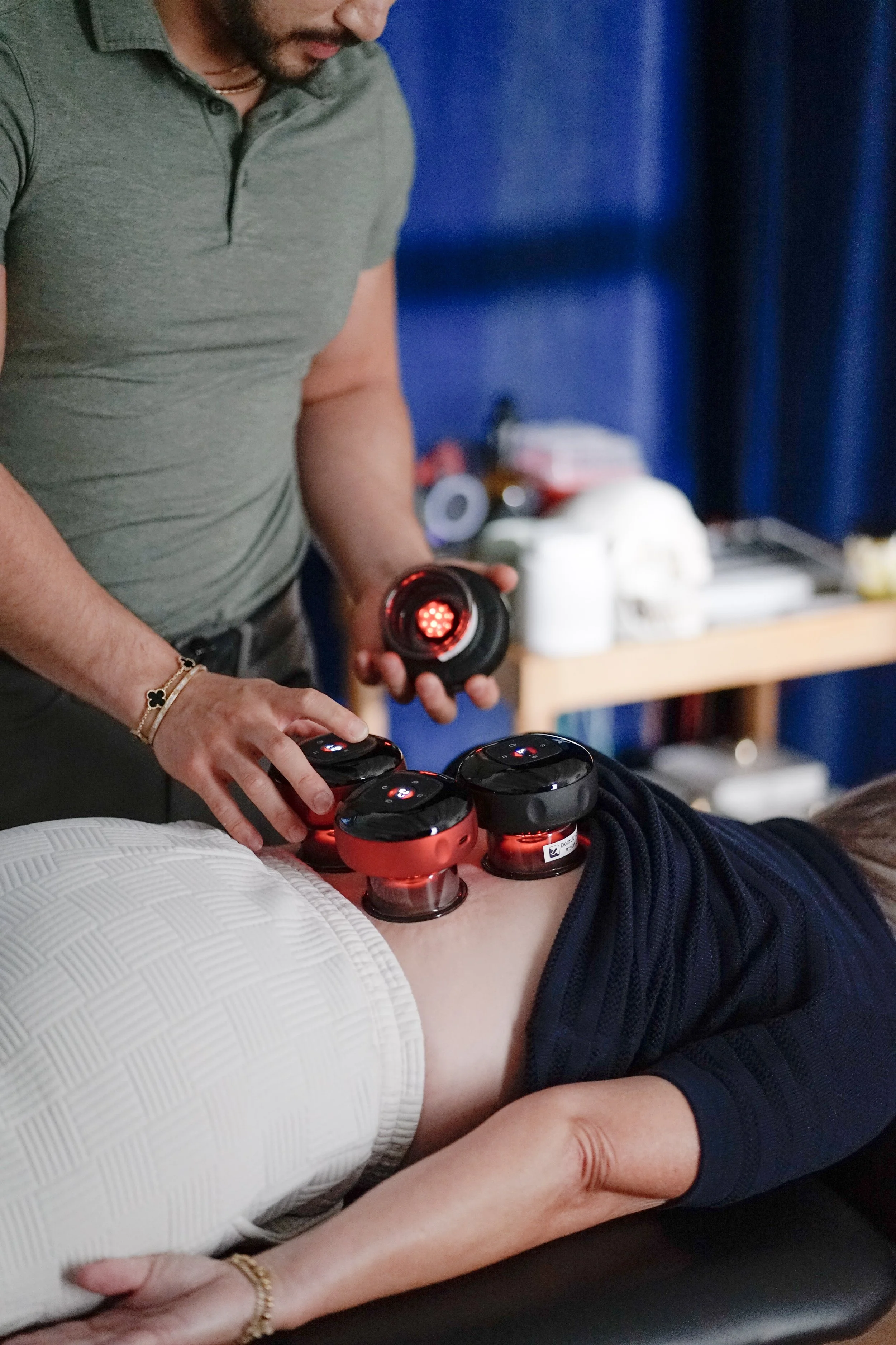 A chiropractor in a white polo shirt performs a neck adjustment on a woman lying face down on a chiropractic table in a clinic.