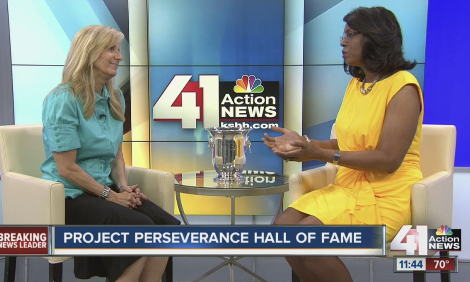 Woman in blue shirt on TV with woman in yellow dress