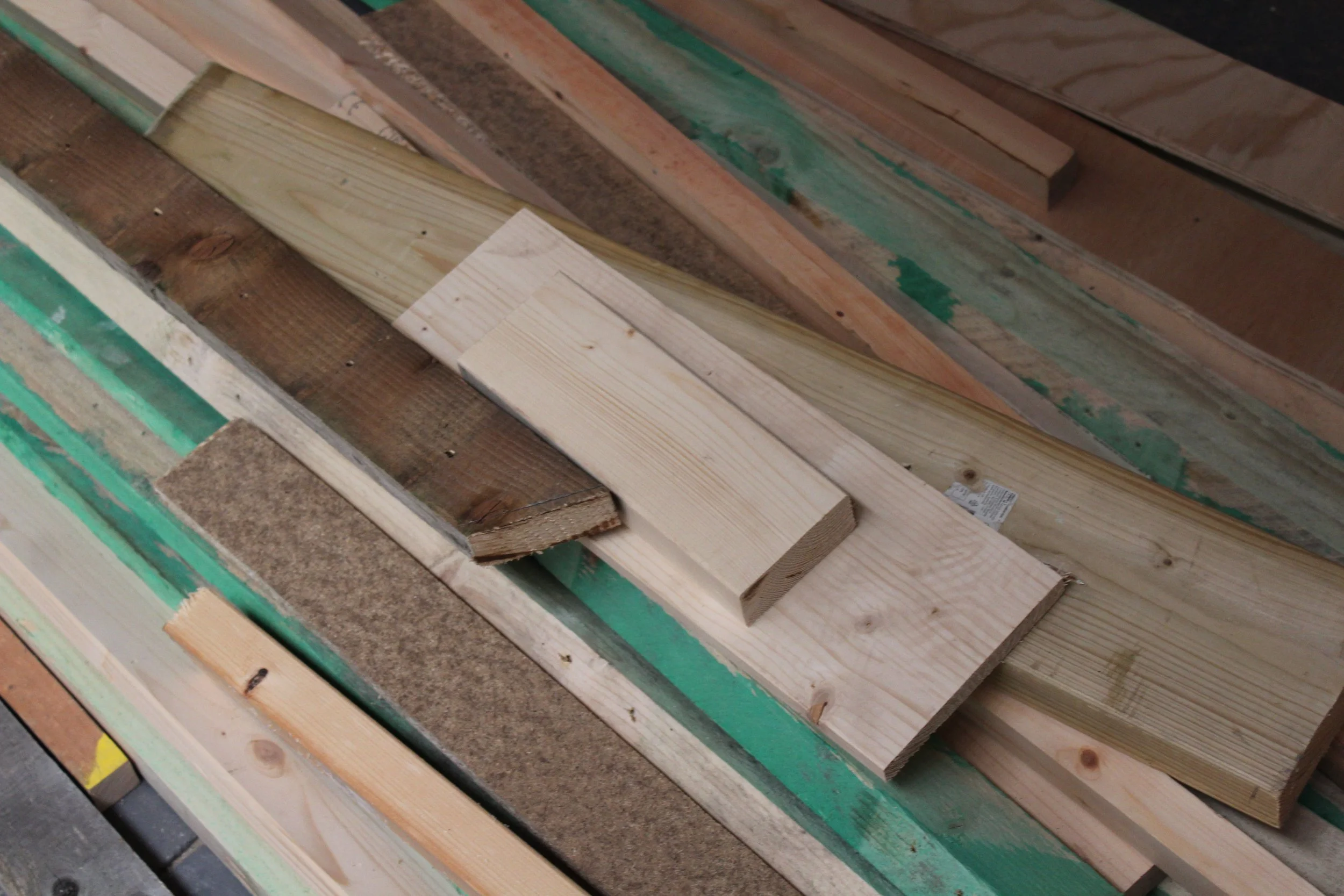 Stacked wooden planks of various sizes and colors on a surface.