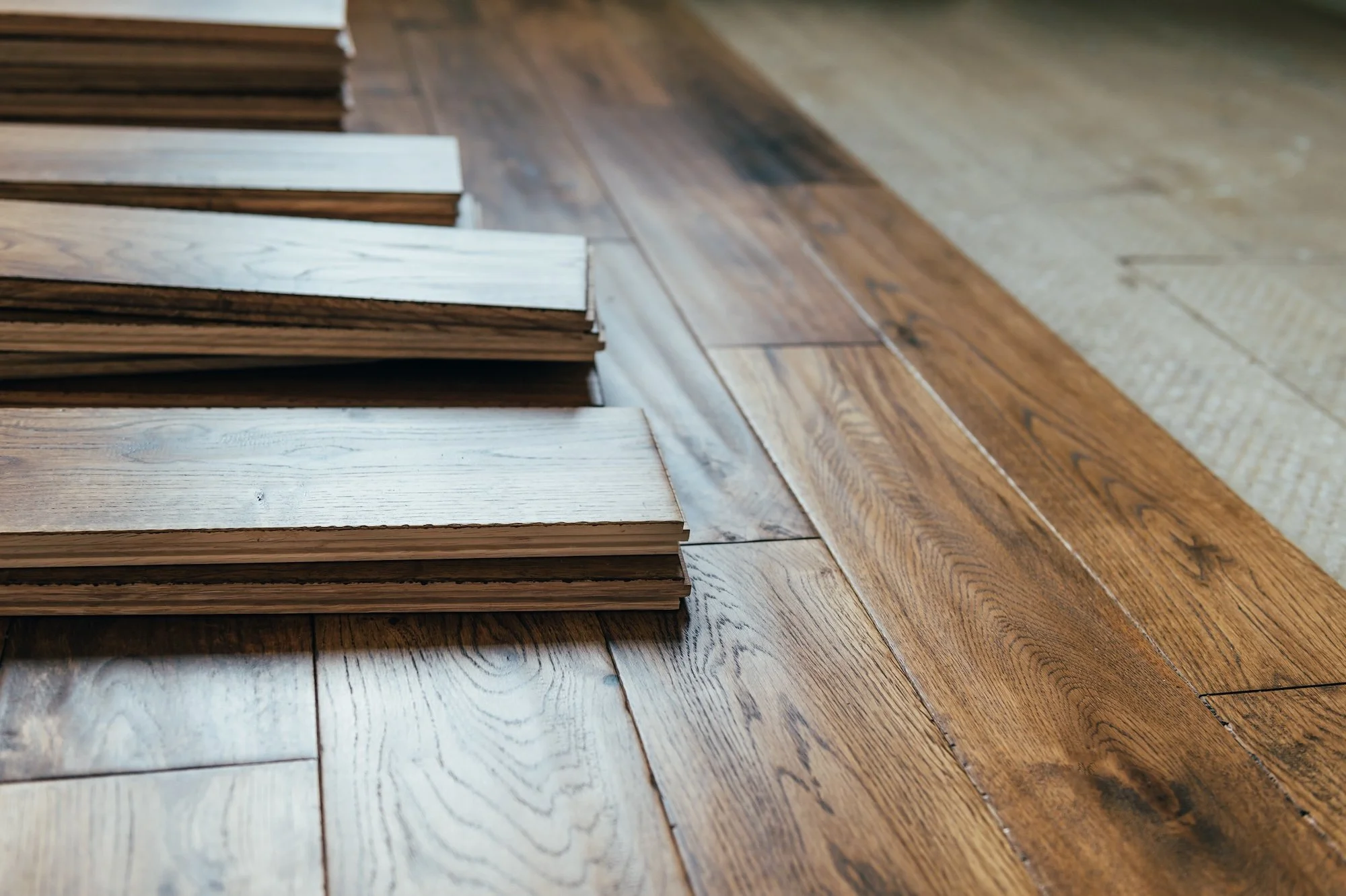 Stacks of wooden flooring planks arranged on a hardwood floor.