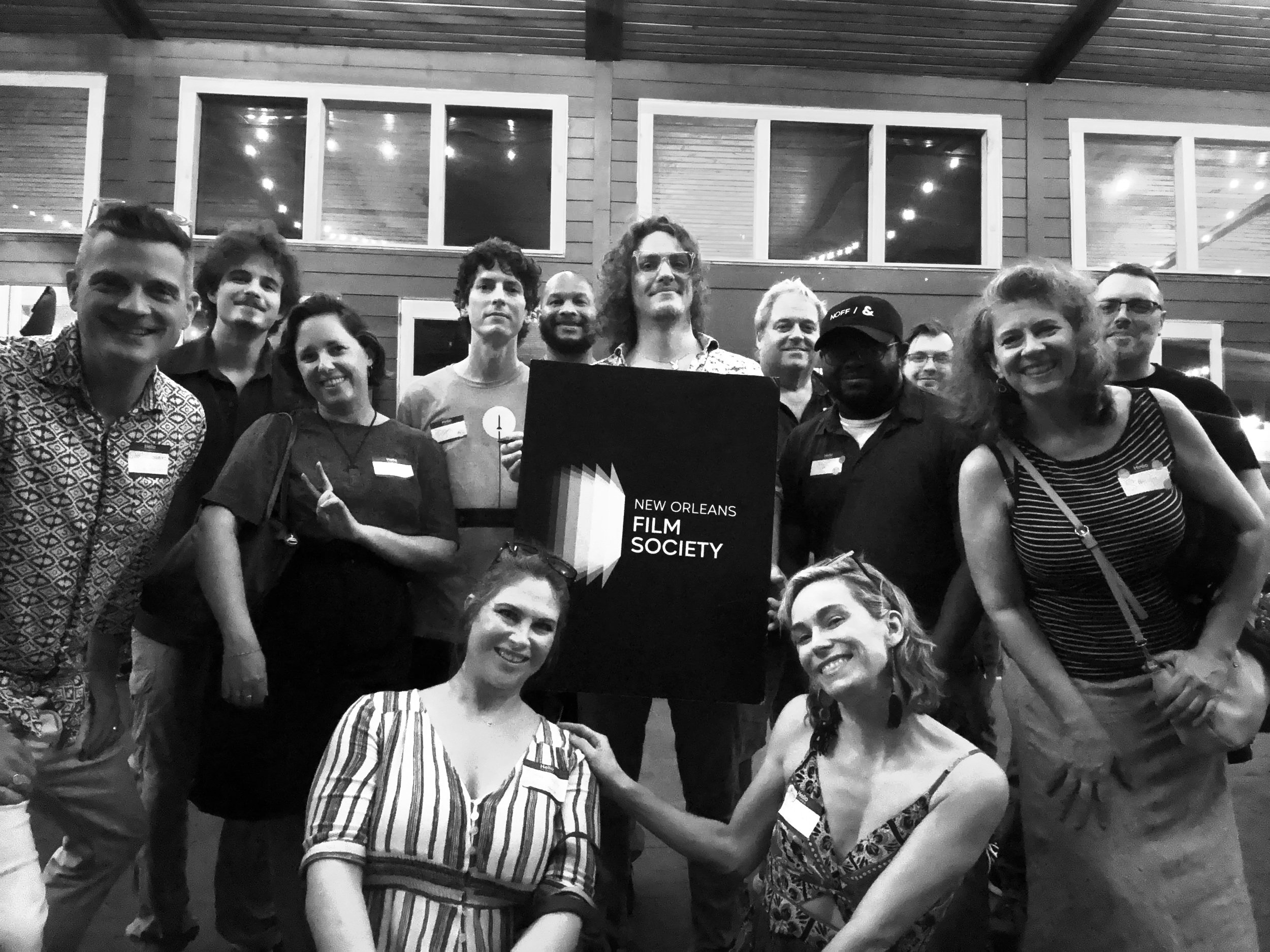 Group of people smiling at an event, holding a sign that reads 'New Orleans Film Society.'