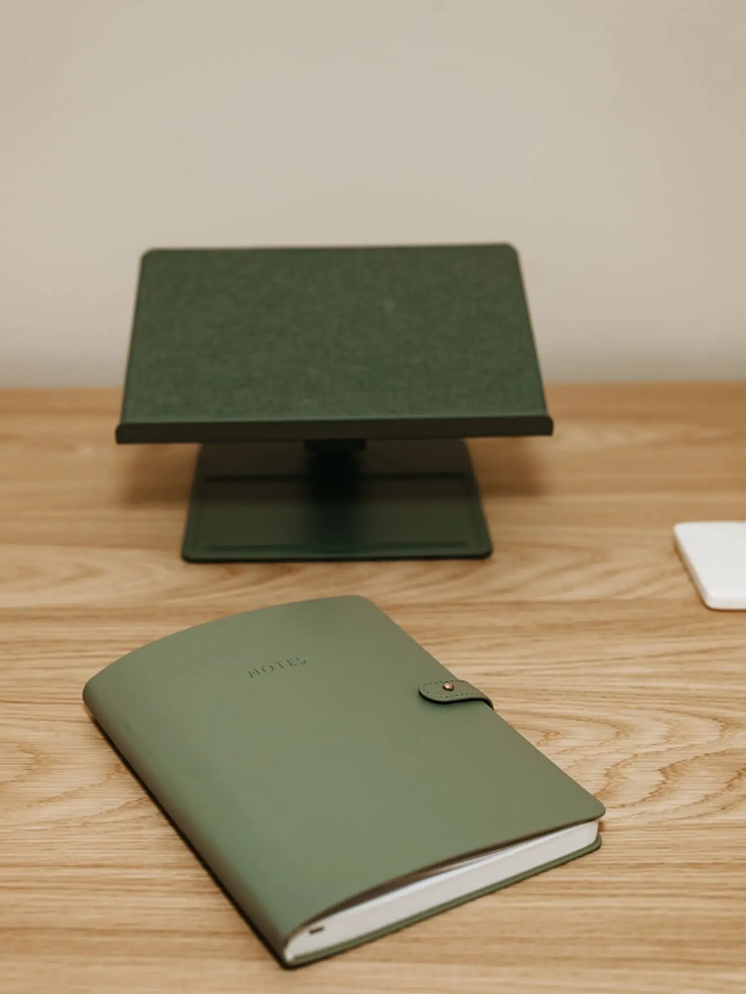A wooden desk with a closed green notebook labeled 'NOTES' and a green digital scale behind it.