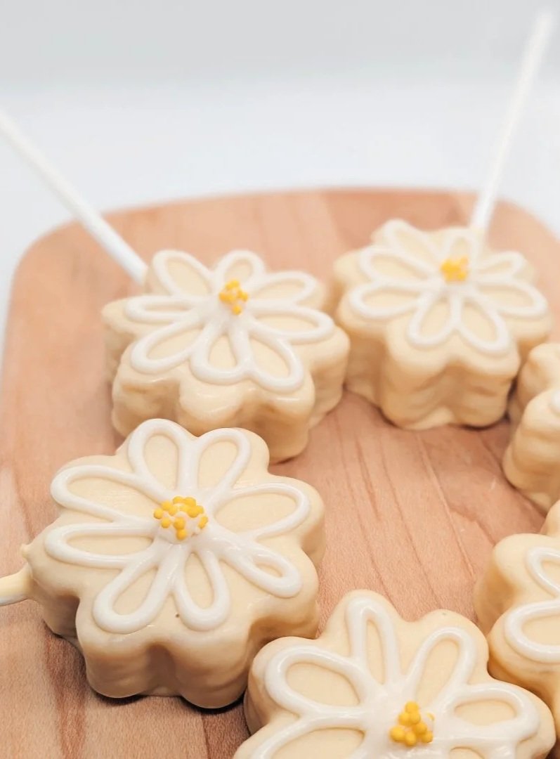 Daisy shaped lemon cake pops arranged in a circle pattern on a wooden board.
