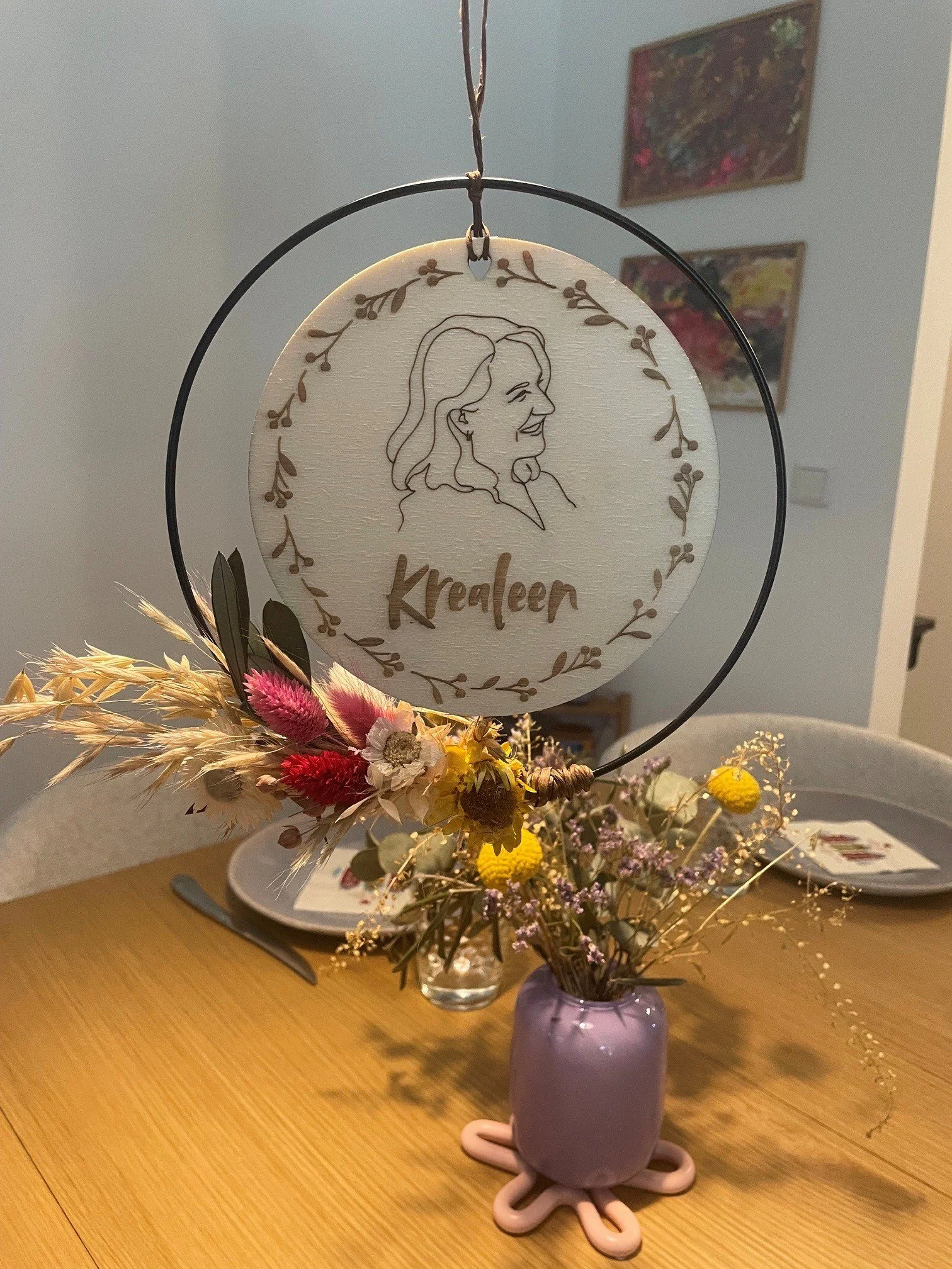 Eine Vase mit Trockenblumen auf einem Tisch, im Hintergrund ein Porzellan-Panel und auf dem Tisch befinden sich Tellern und Besteck.