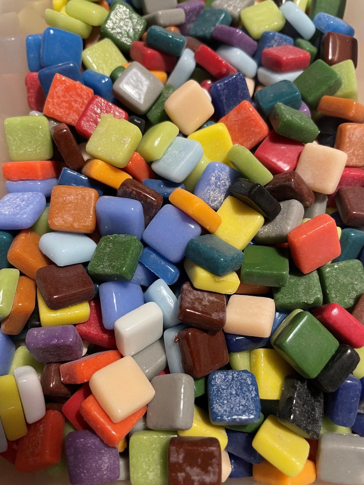 Bunte Kieselsteine in verschiedenen Farben und Formen, überwiegend rechteckig, auf einer Oberfläche. 