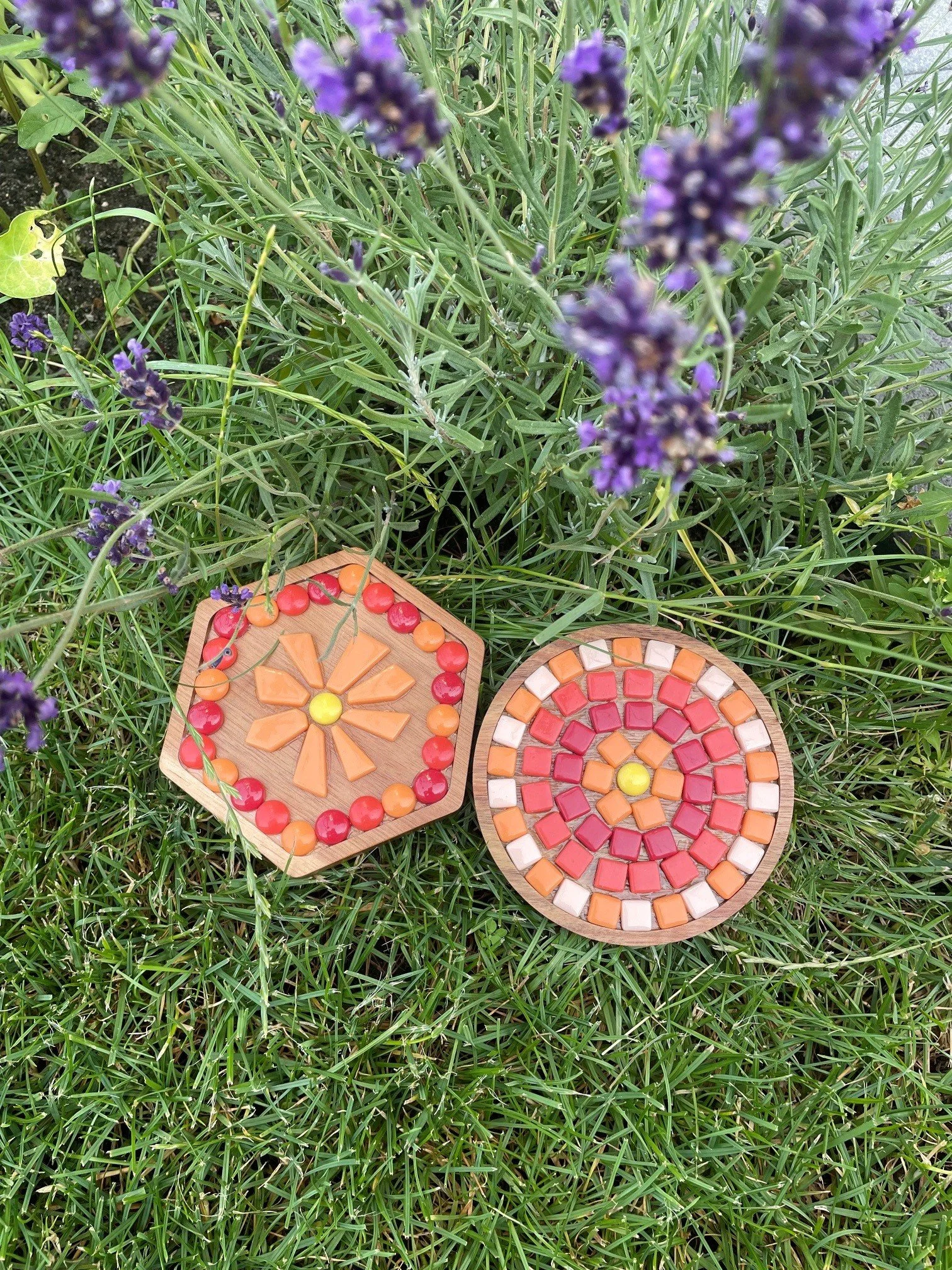 Bunte Mosaik-Couchtische auf grünem Gras, umgeben von Lavendelpflanzen