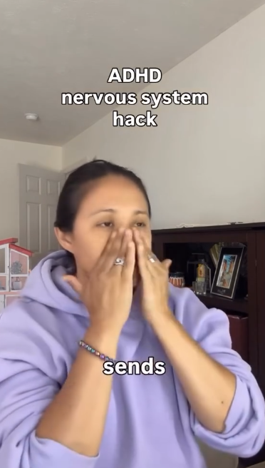 A woman with dark hair wearing a purple hoodie is covering her face with her hands. Text on the image reads 'ADHD nervous system hack sends'.