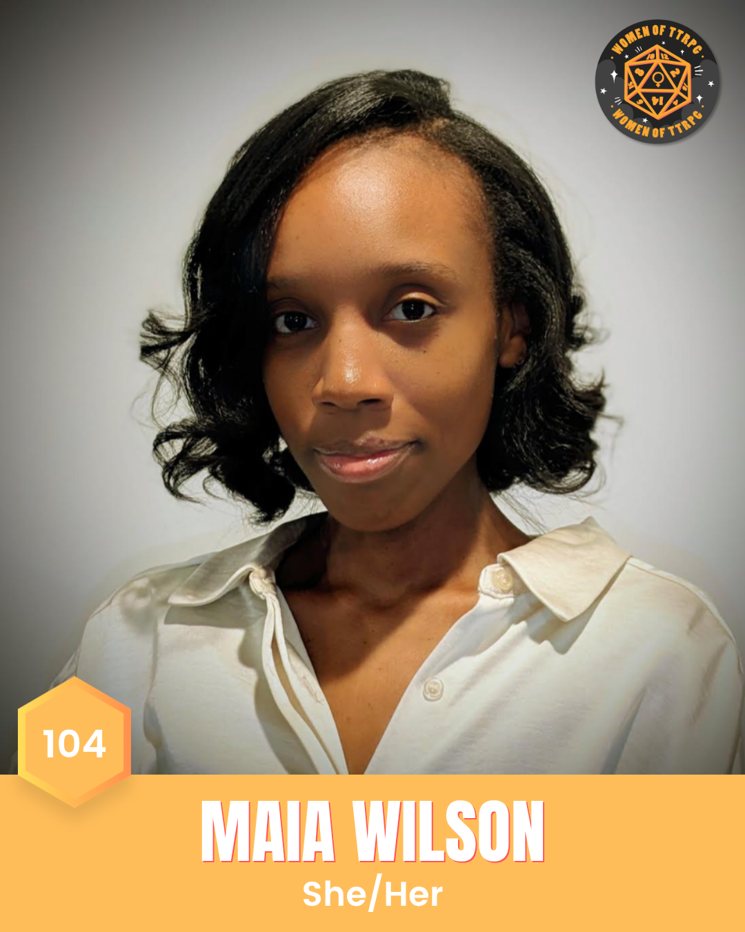 Maia Wilson (she/her) has black curled hair, brown eyes, and is wearing a white collared top with the top few buttons left open. She is smiling in front of a grey background.