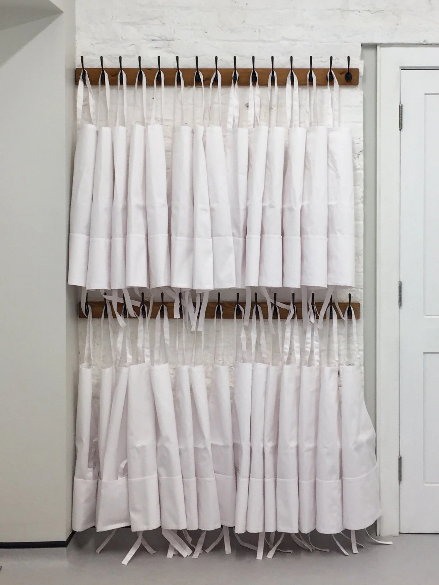 Children's aprons hanging on a wooden rack at Kelmarsh Hall, ready for school visits.