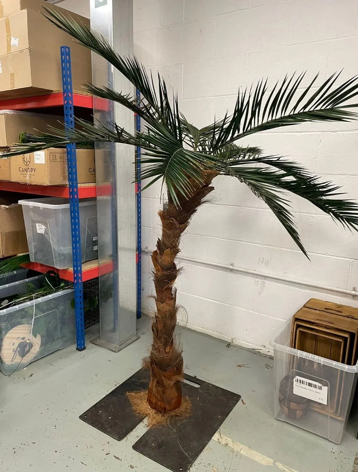 Artificial palm tree made with a copper pipe armature and dried palm bark, with long arching fronds made from preserved Phoenix palm leaves.