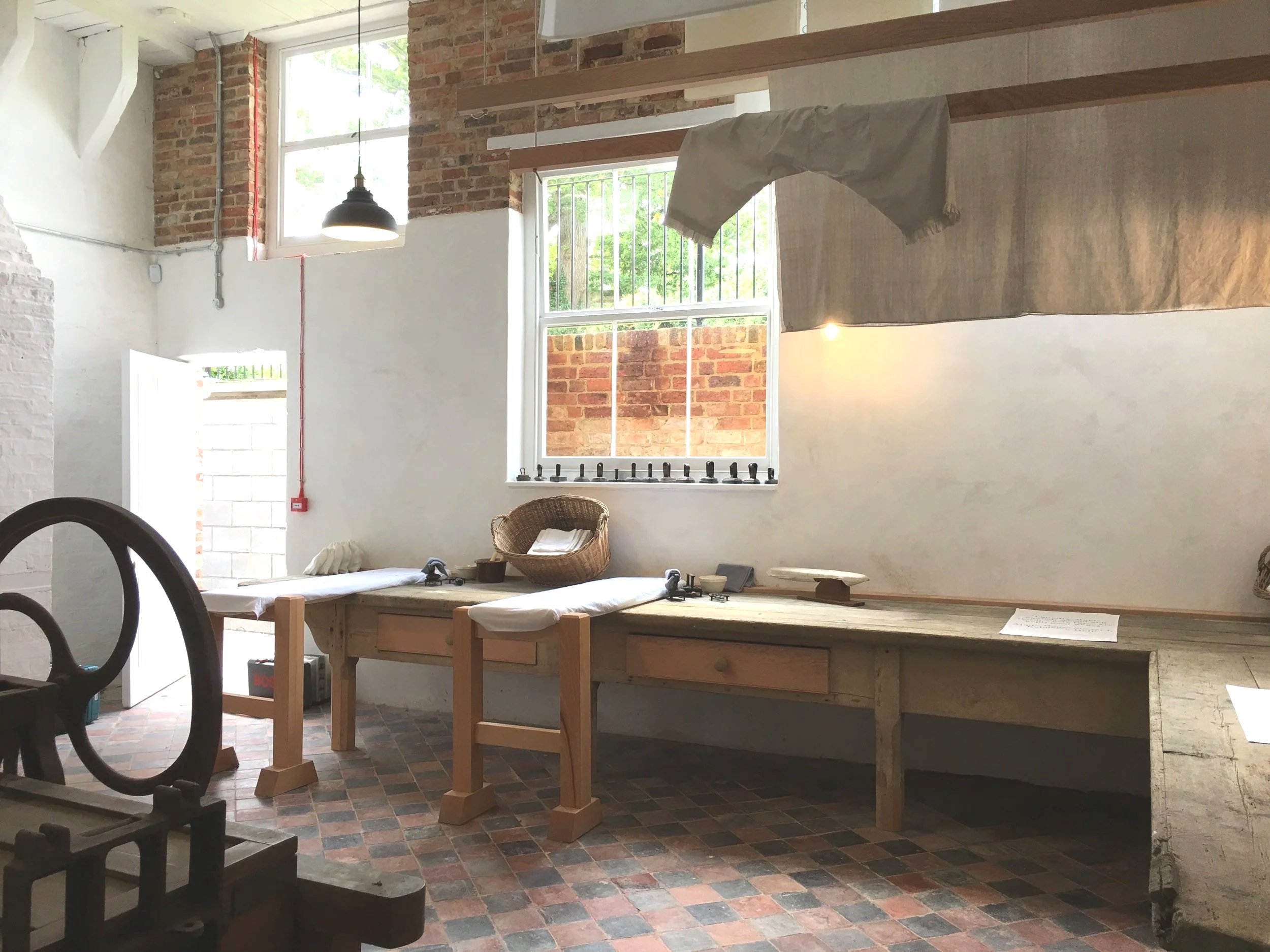 Historic laundry ironing area at Kelmarsh Hall, with a worktable and traditional laundry equipment.