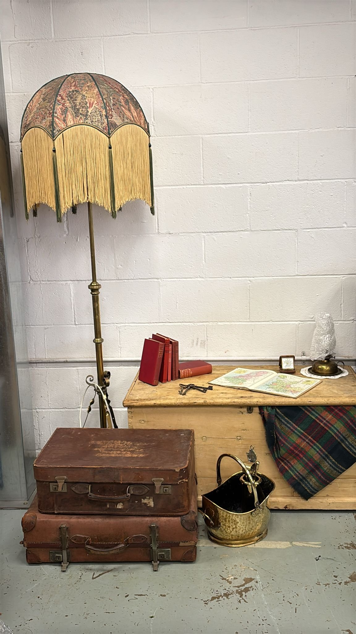 Selected props for a vintage Christmas scene with vintage standing lamp, a wooden chest, a desk with books, an open map, a small clock and a plaid blanket.