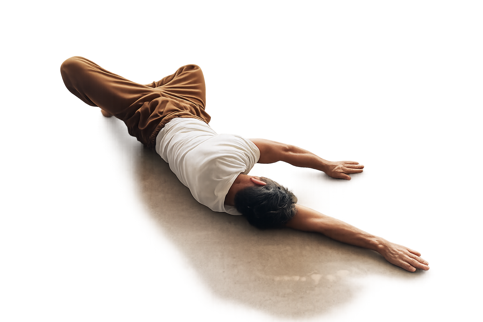 Une personne allongée sur le côté en position de yoga, bras étendus devant elle, portant un t-shirt blanc et un pantalon marron, sur un sol beige.