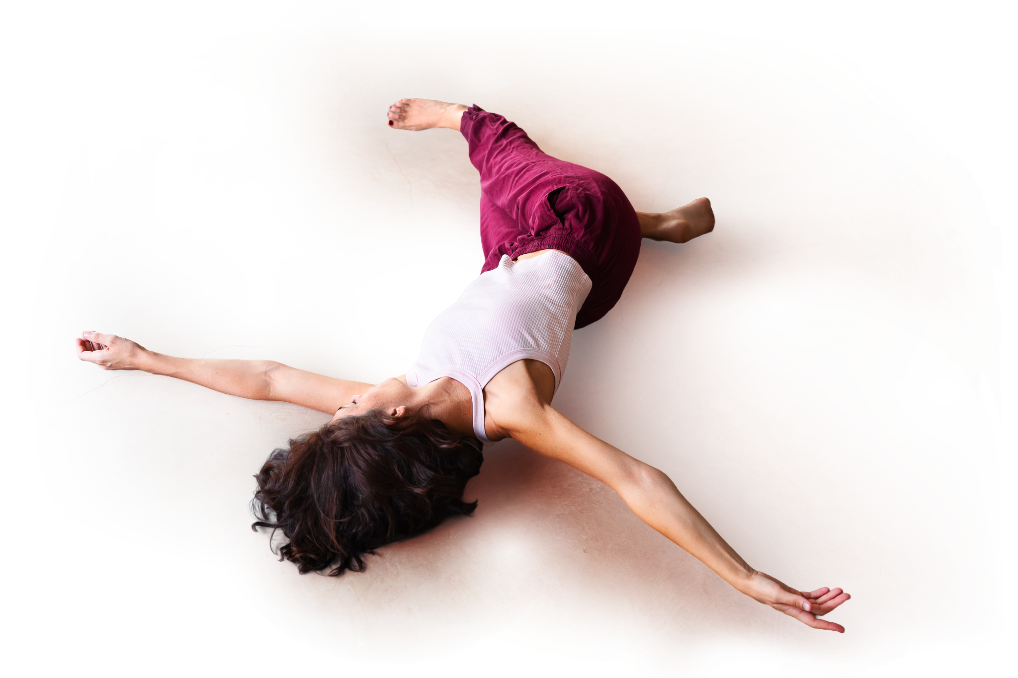 Une femme pratiquant le MUNZ FLOOR allongée sur un sol en béton, étirement avec un bras tendu en avant et un bras plié derrière la tête.