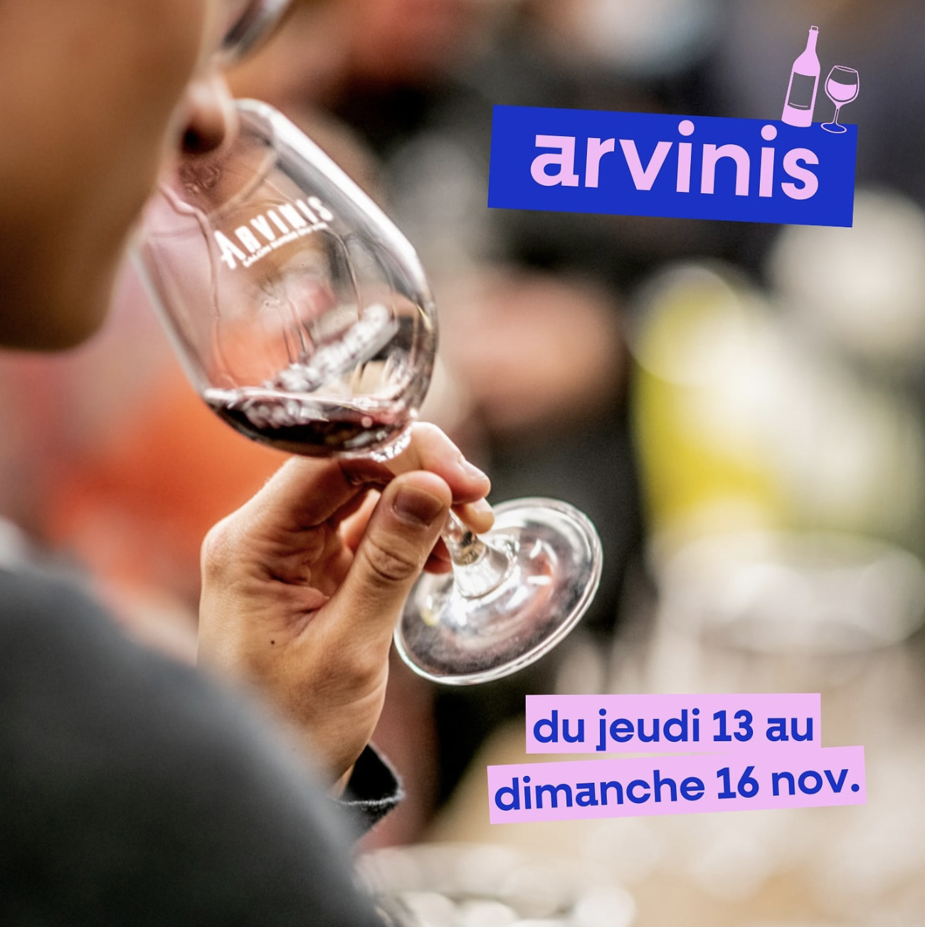 Une personne tenant un verre de vin rouge lors d'un événement. Le texte indique qu'Arvinis se tient du jeudi 13 au dimanche 16 novembre.