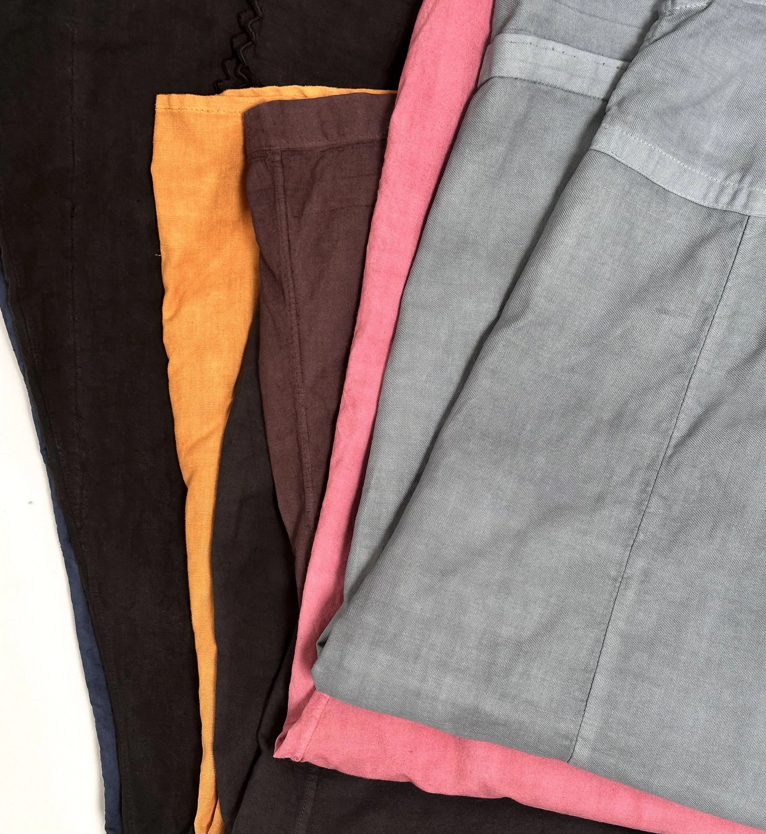 detail of stacked fabrics in black, orange, burgundy, pink, and gray colors, laid flat.