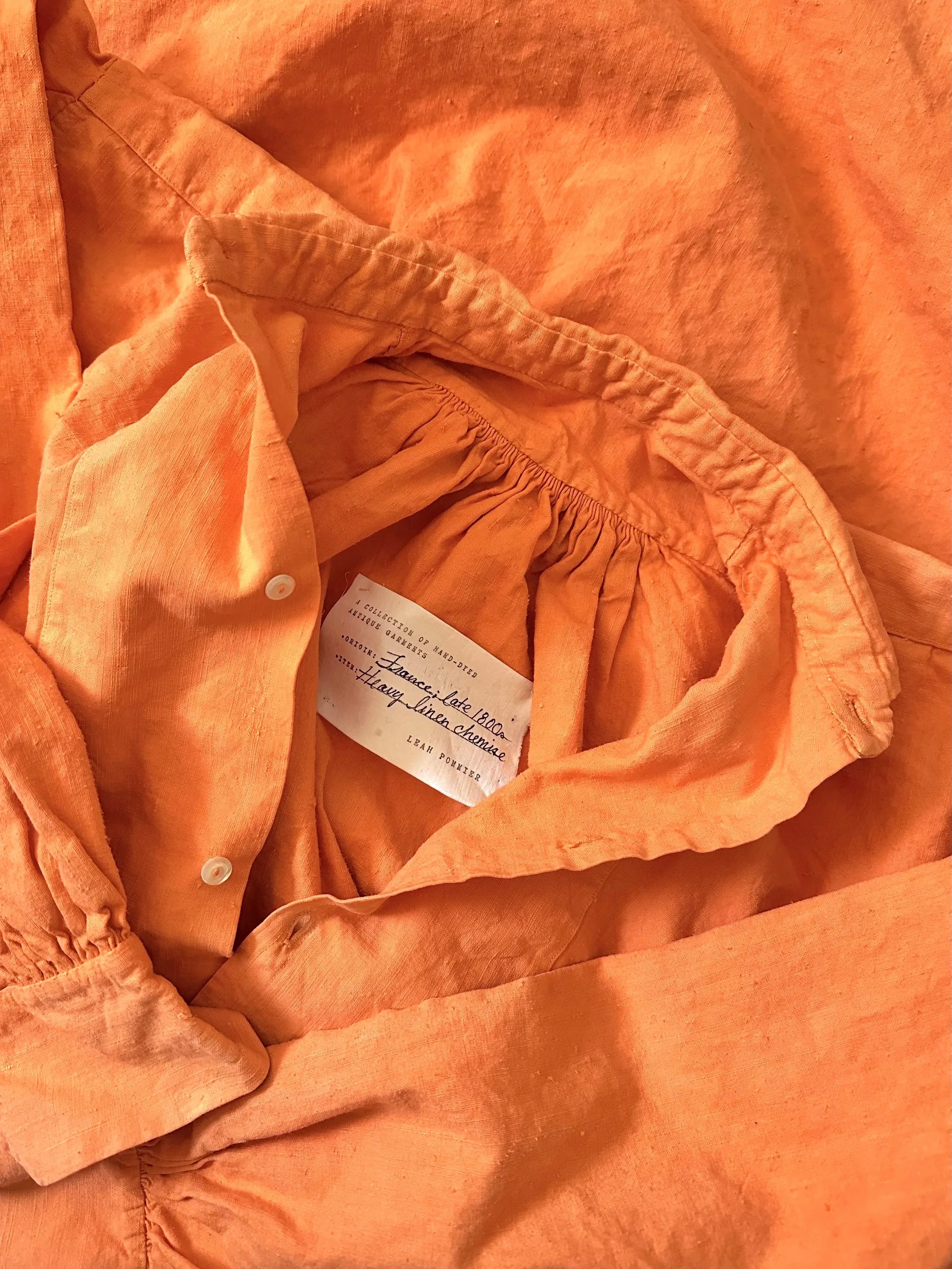 An antique orange linen shirt from the late 1800s made of linen.