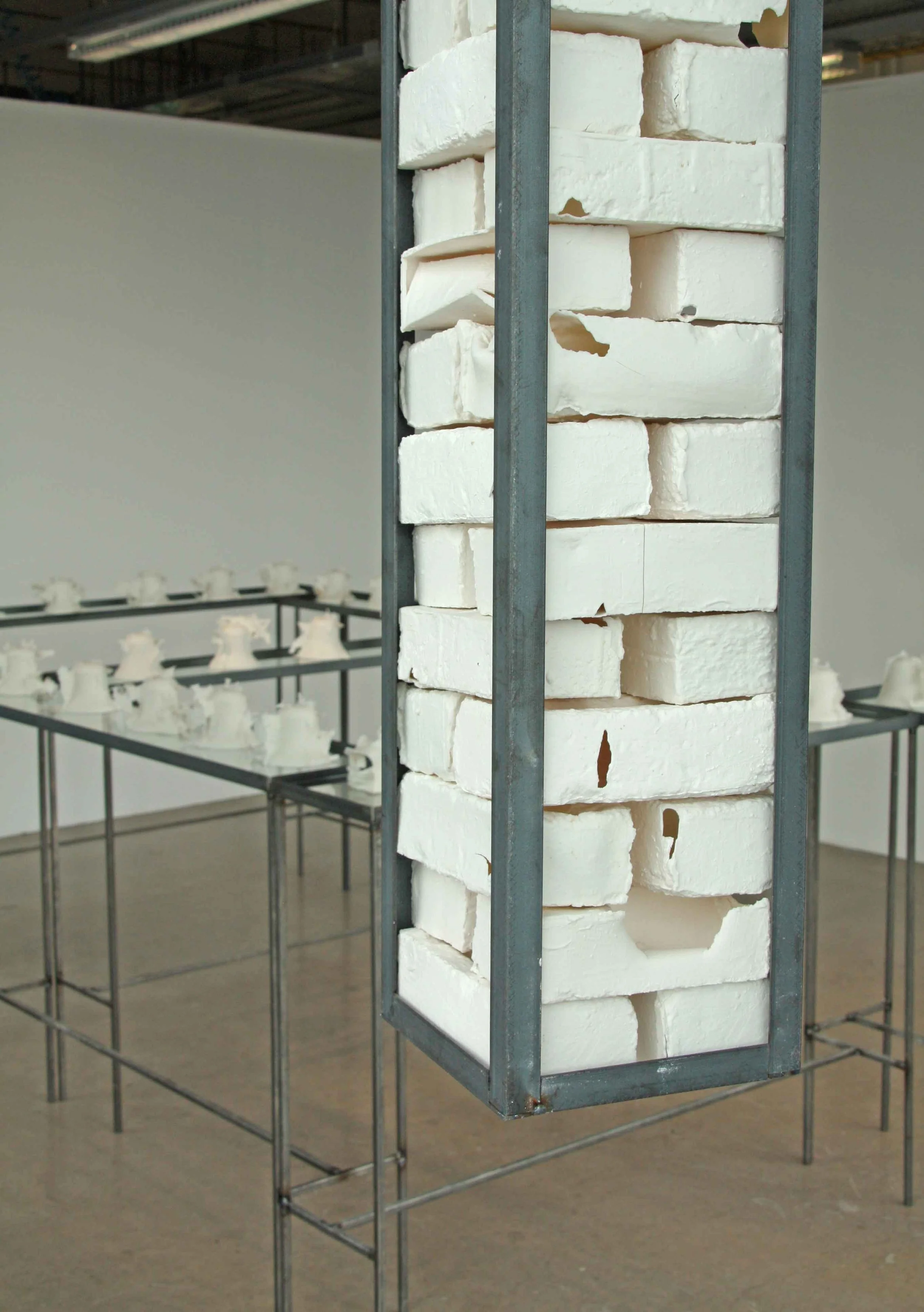 White brick-like sculptures displayed on a metal structure in an art gallery or museum.