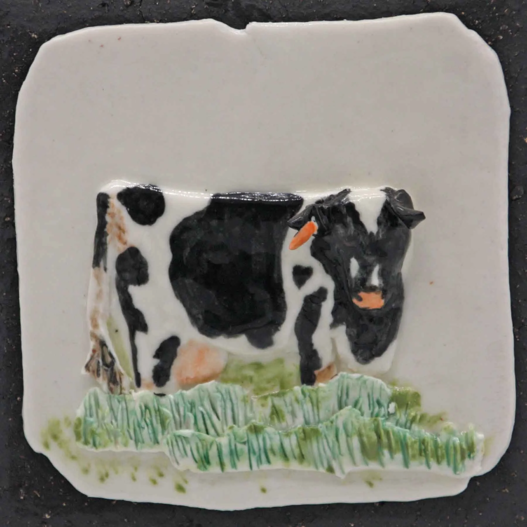 Black and white cow design on a white ceramic til