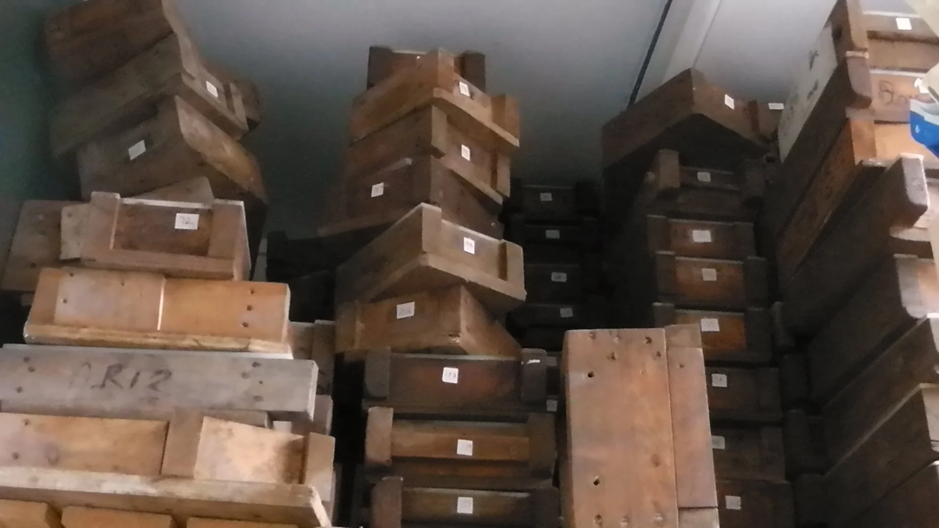 Stacked wooden blocks or furniture pieces with visible labels or tags in a storage area or warehouse.
